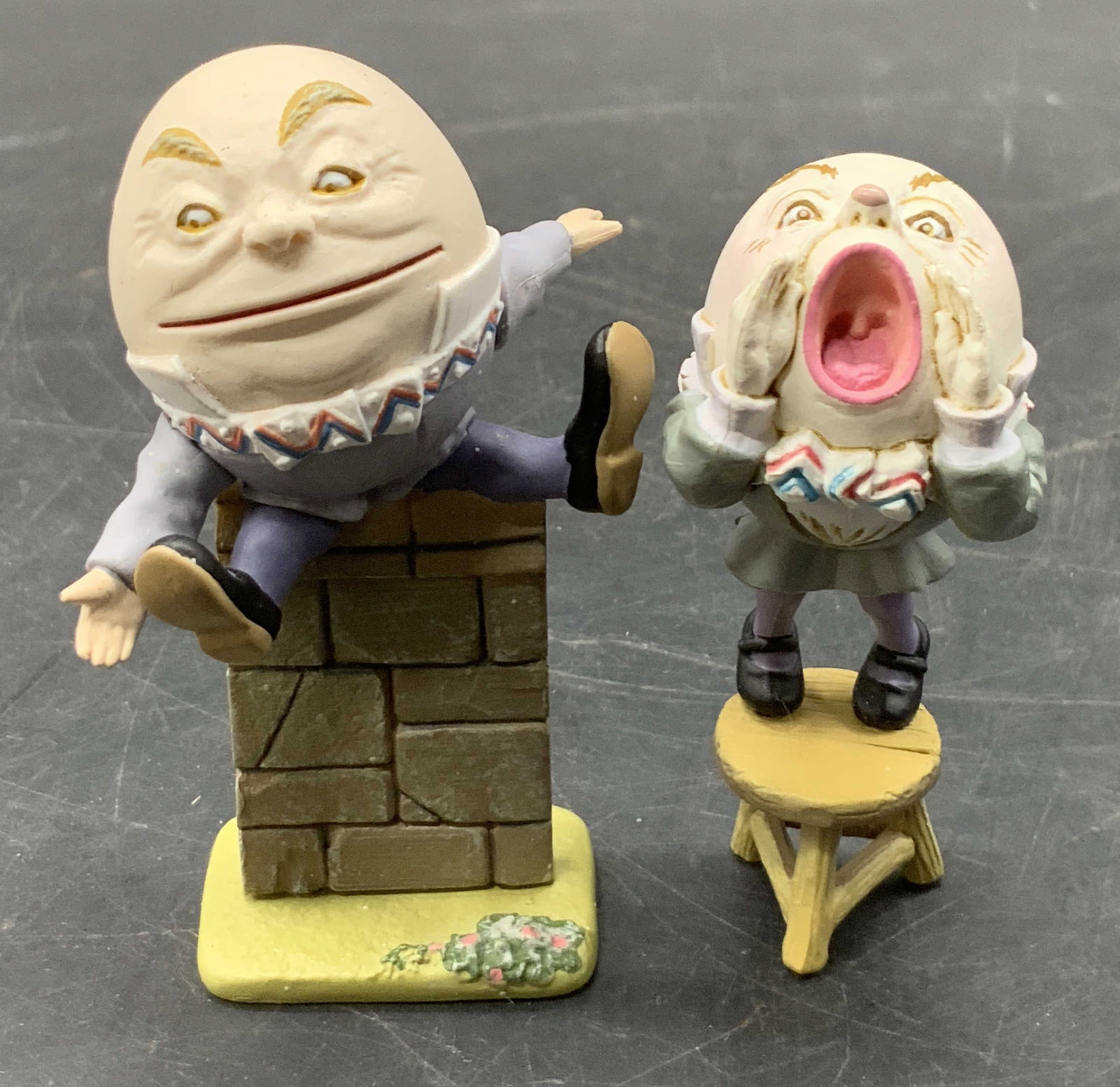 Lot 2 Humpty Dumpty Figurals, KAIYODO & More: Two composite Humpty Dumpty figurals. One is depicted sitting on a wall and the other is depicted standing on a stool. Largest piece measures approx. 2.5H x 2W in. Width measured arm to arm. One figur