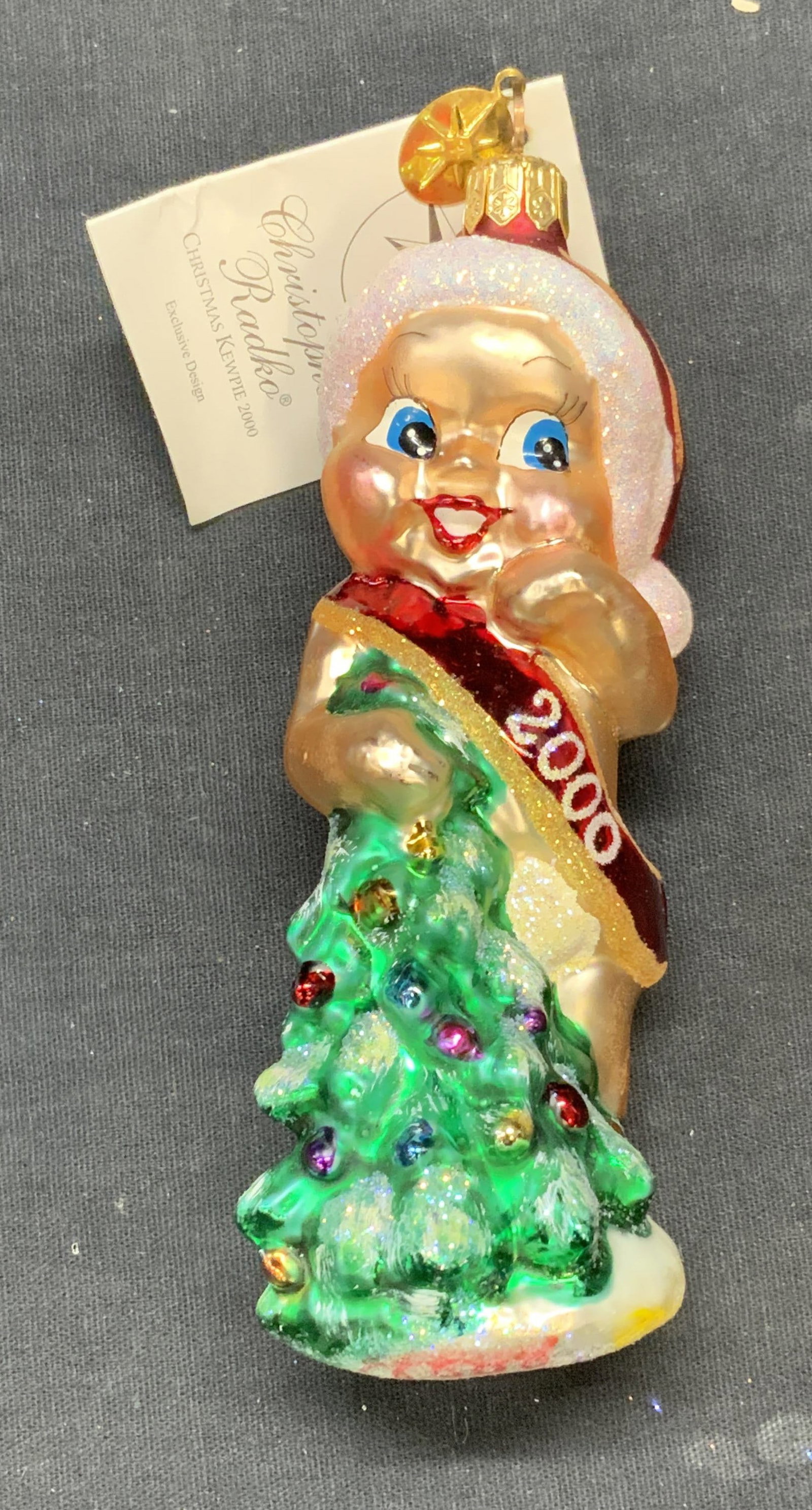Christopher Radko Glass Baby Ornament, 2000: Christopher RADKO Christmas Kewpie glass baby motif ornament. Produced 2000. Measures approx. 5 inches long. Includes original box. Some surface wear including scratching observed. Christopher RADKO, 