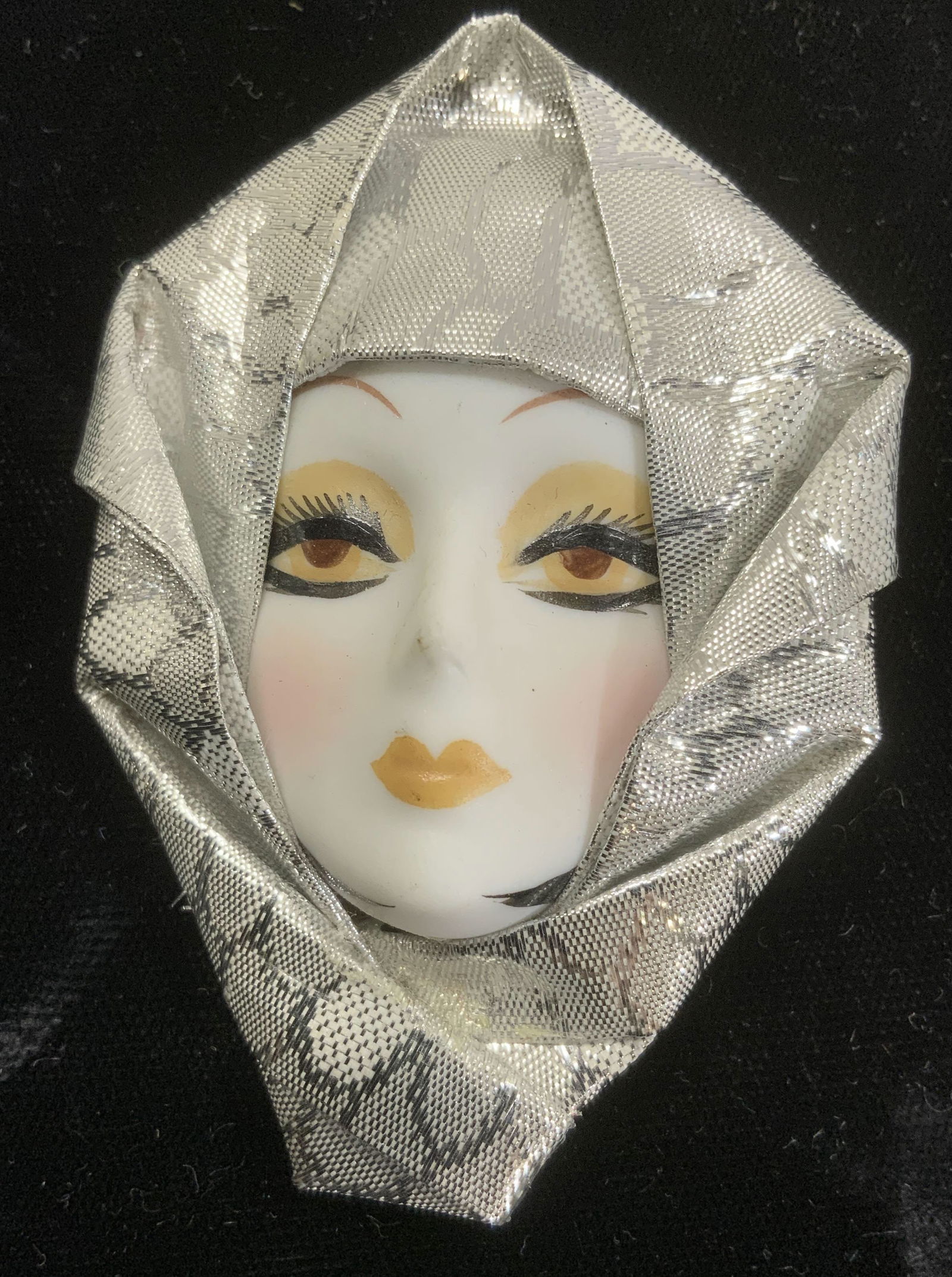 Hand Painted Porcelain Face Brooch: Hand crafted and hand painted porcelain face brooch with metallic silver fabric over face. Art Deco brooch . Measures 3 x 2 in. Property of Trump Tower Manhattan and Bedford, NY Estates Hand painted P