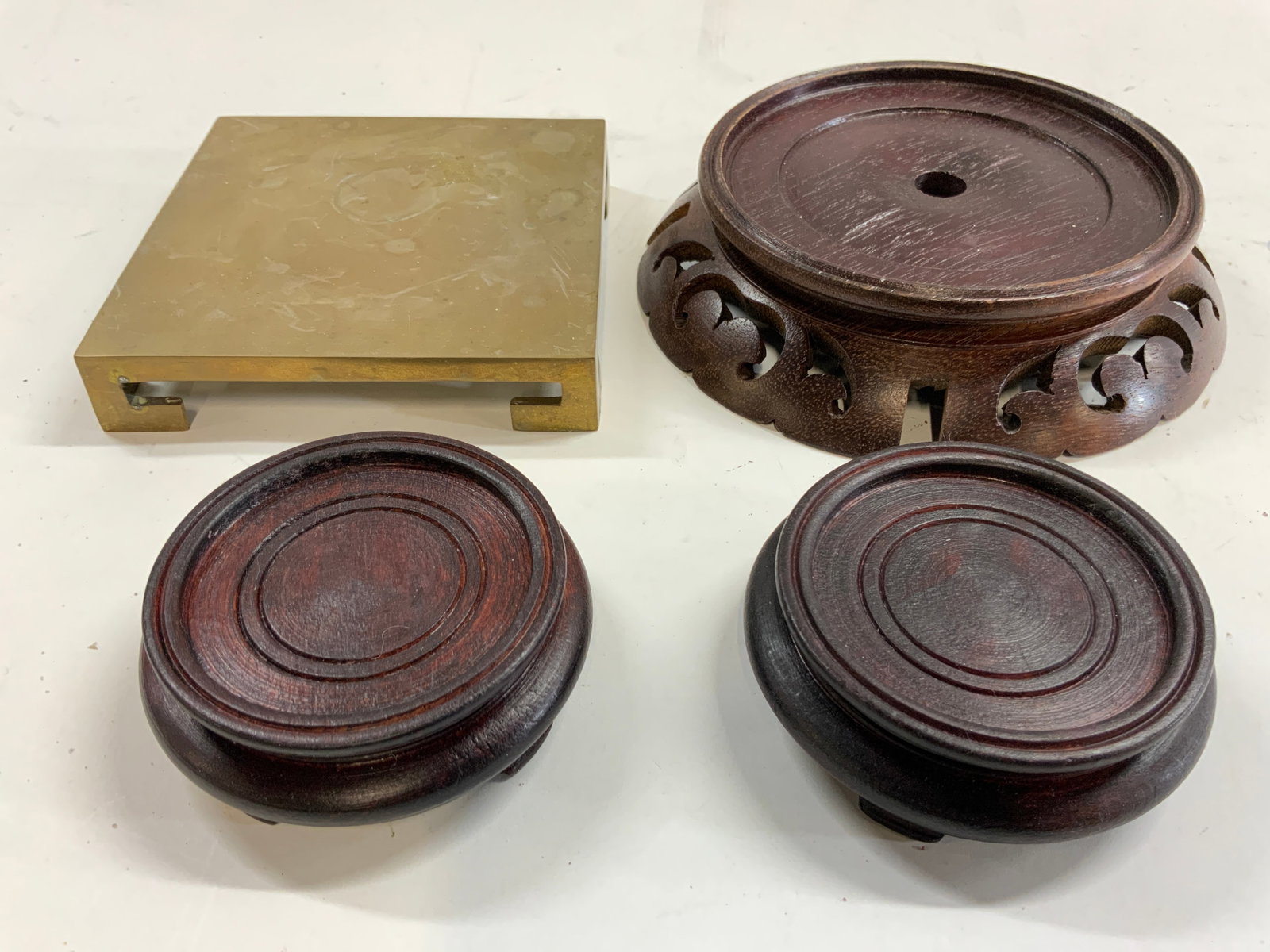 Lot 4 Asian Wooden & Gilt Metal Pedestals: Lot includes 3 wooden pedestals and 1 gilt metal pedestal appears to be brass. Each wooden pedestal is brown toned. Smaller pedestals have 4 feet, larger wooden pedestal has pierced detail. Largest pi