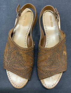MIU MIU Brown Leather Studded Sandals: MIU MIU brown leather sandals with studded flower motif. Size 10.5. Some wear to leather and soles consistent with exposure. Includes shoe box. MIU MIU, MIU MIU sandals, MIU MIU shoes, ladies designer