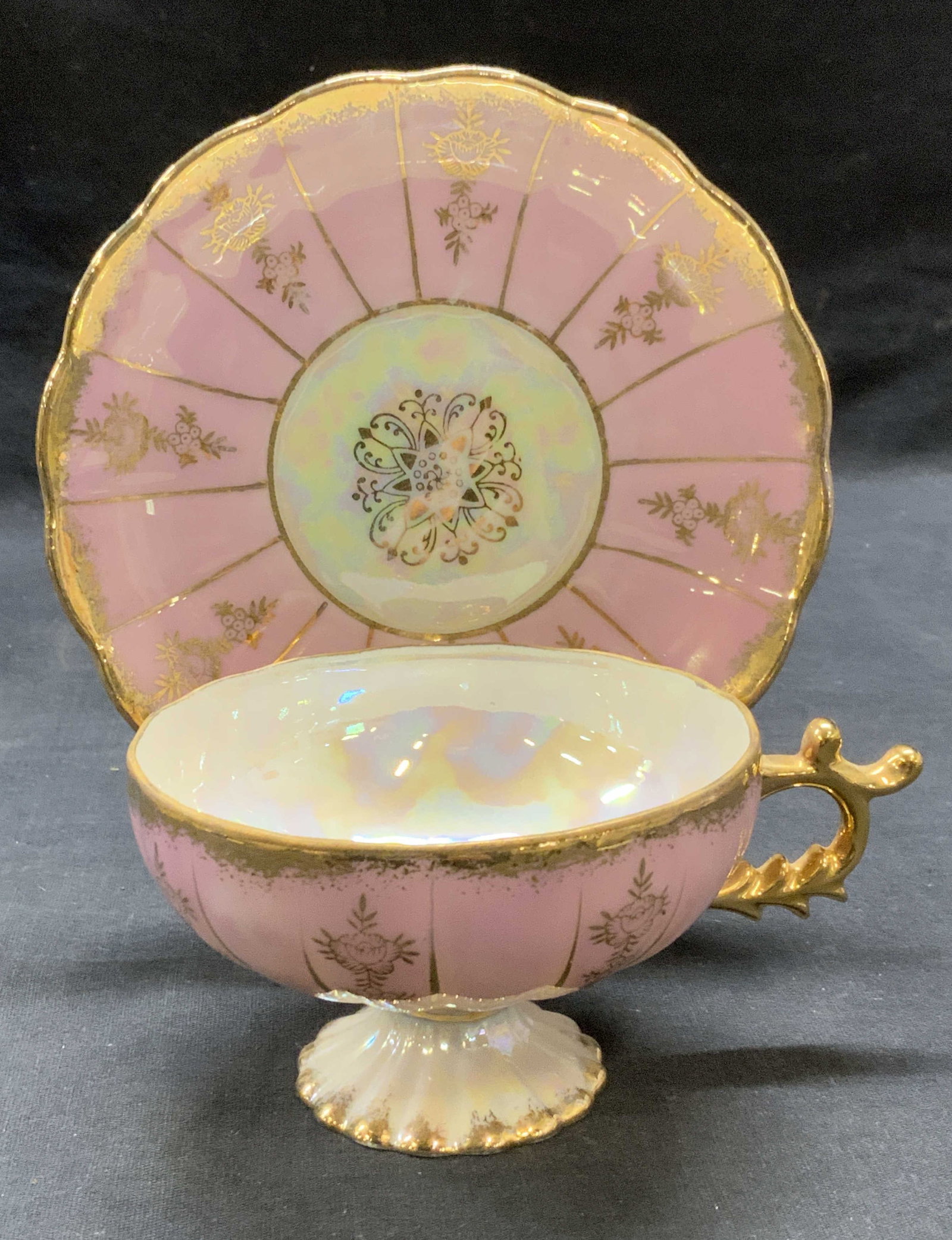 Vintage Pink Gilt Porcelain Teacup & Saucer: Vintage pink gilt porcelain teacup and saucer with floral scroll motif. Saucer measures approx. 5.75 inches wide. Cup measures approx. 4 x 2.25 inches. Some surface wear including scratching observed 