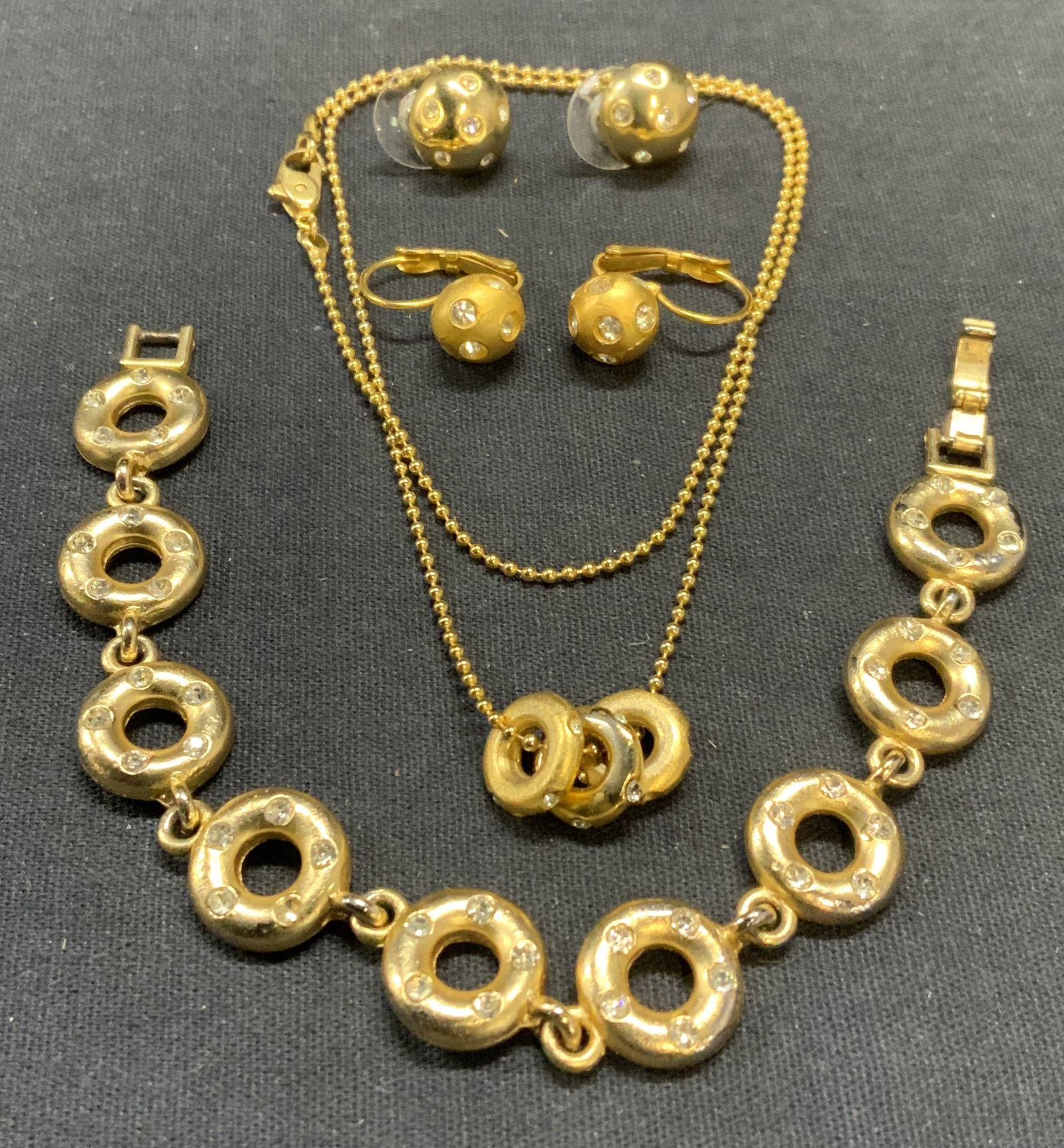 Lot 4 Gold Tone Crystal Necklace & More: Lot of 4 gold tone and colorless crystal d3corateddecorated jewelry pieces. Includes necklace, bracelet, and 2 pairs of earrings. Necklace drop length approx. 8.5 inches, bracelet measures approx. 6.5