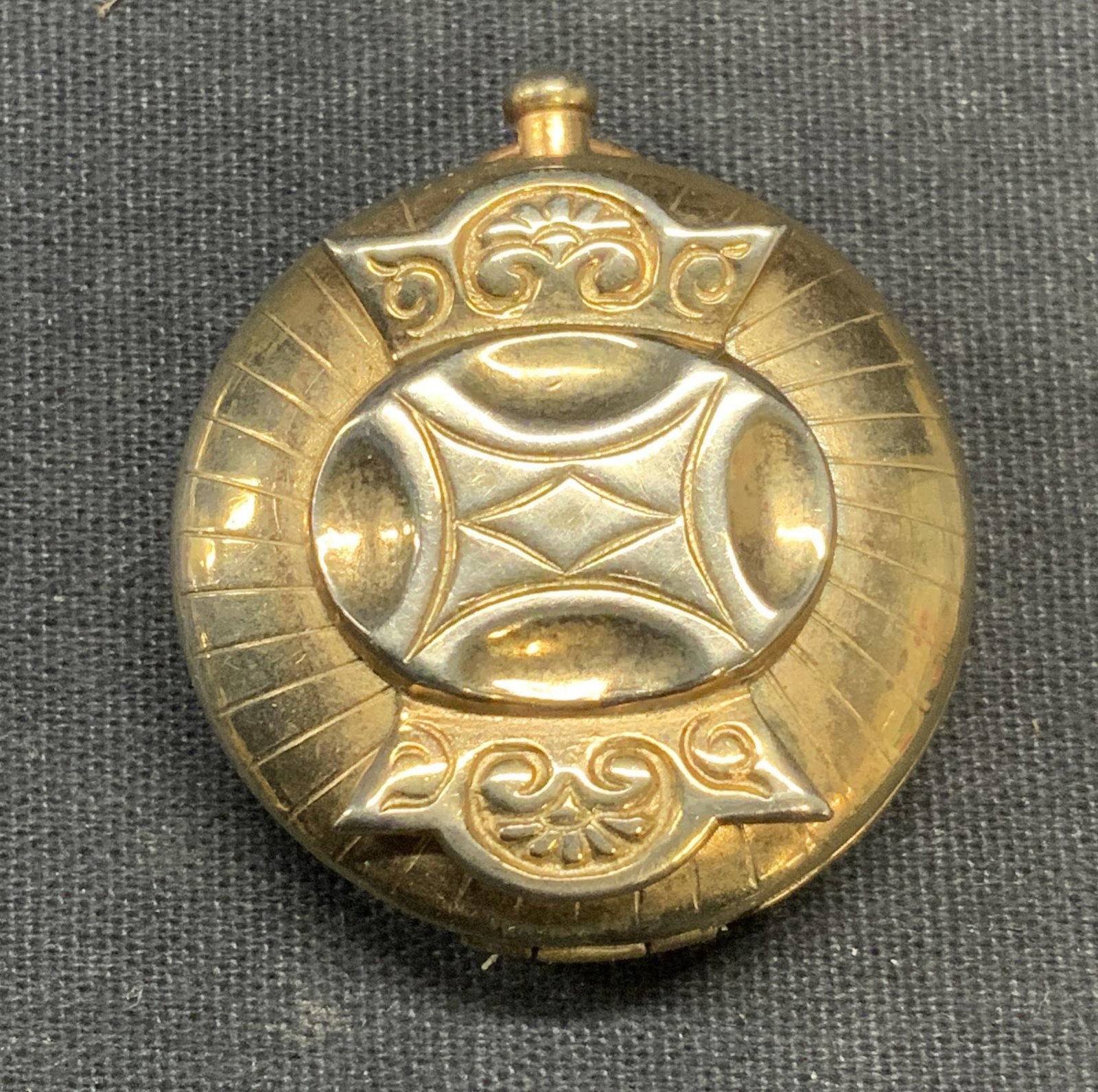 Vintage Gold Tone Locket Pendant: Vintage gold tone locket pendant. Raised scroll motif on cover. Measures approx. 1.25 inches wide. Some surface wear including scratching observed. Estate jewelry, costume jewelry, cocktail jewelry, f