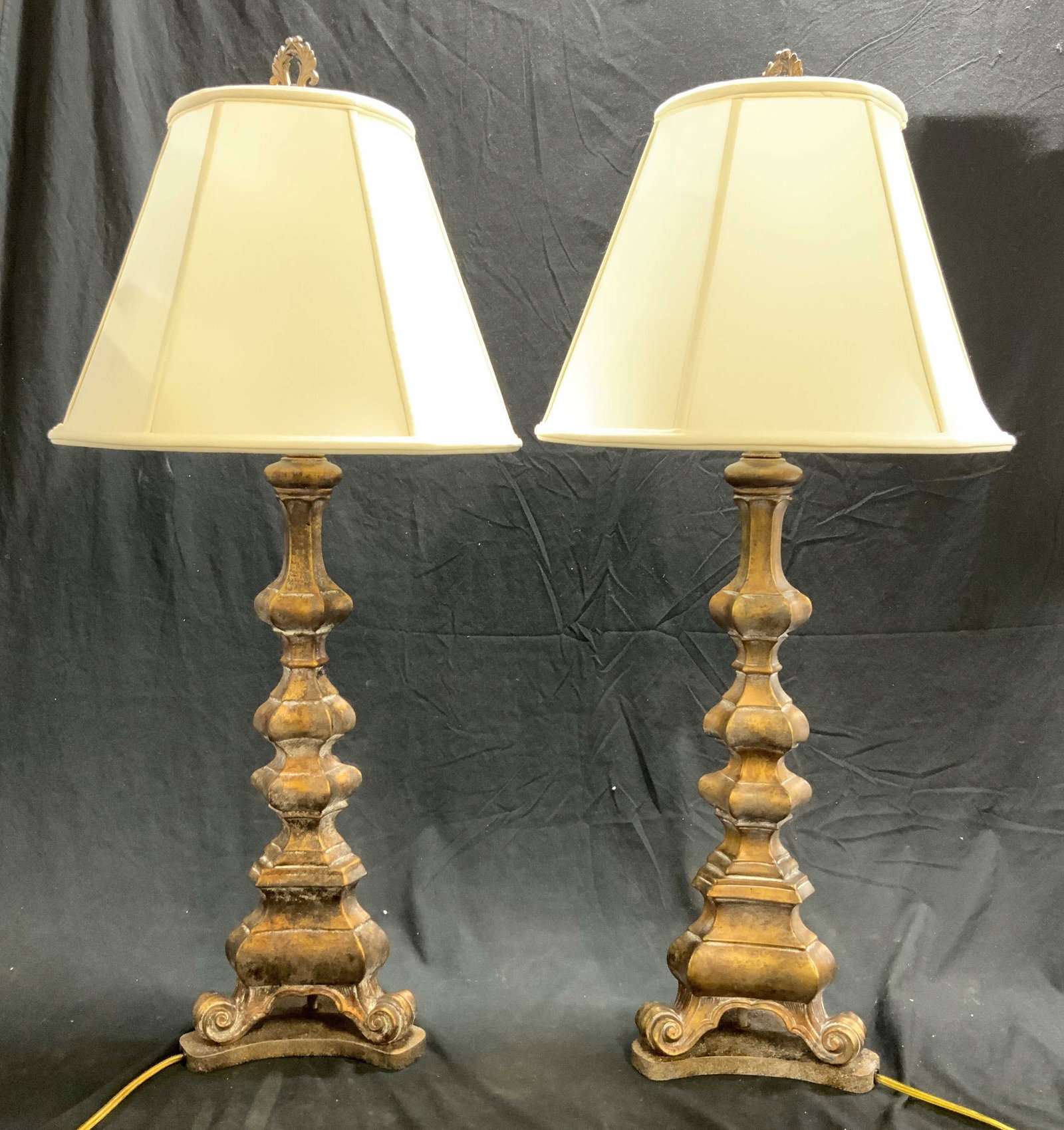 Pair Victorian Gilt Wood Lamps W Shades: Lot includes 2 lamps. Each are giltwood. Lamps each include cream toned shades & curled feet & leaf form finials. Lamps each measure approximately 36 inches tall 9 inches wide without shades 16.5 with