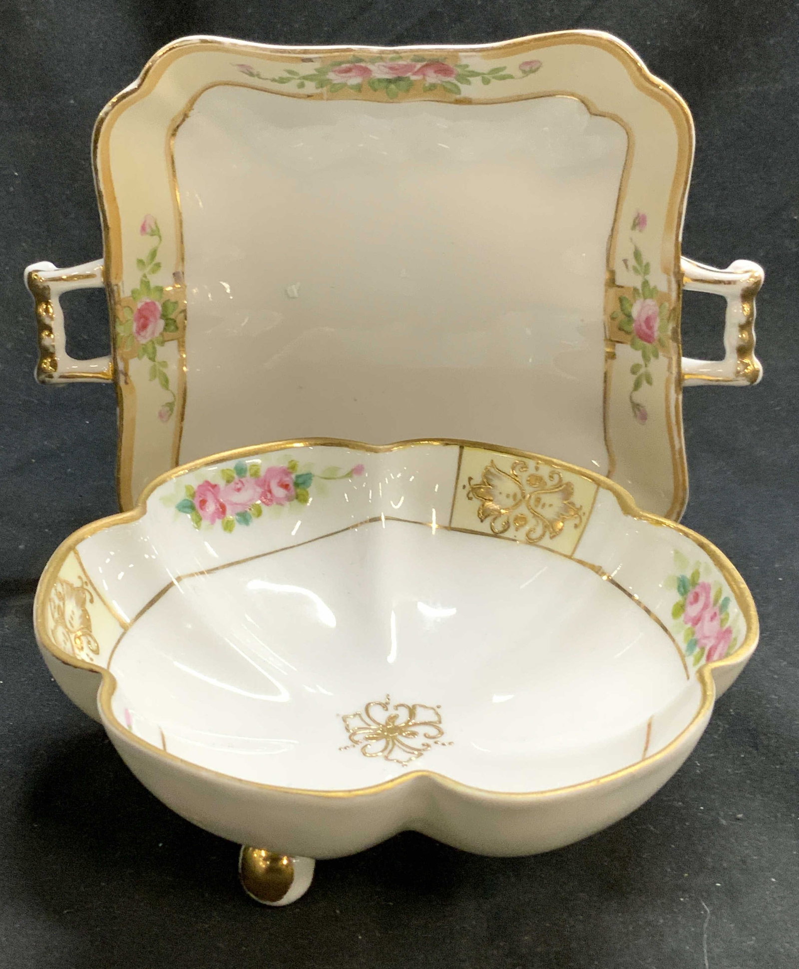 NIPPON Lot 2 Vntg Hand Painted Porcelain Vessels: Underside of each piece is marked NIPPON HAND PAINTED. Lot Includes 1 floral form vessel with gilt, floral and leaf detail. Piece is footed with 3 spherical shaped feet. Lot also includes 1 bowl with 