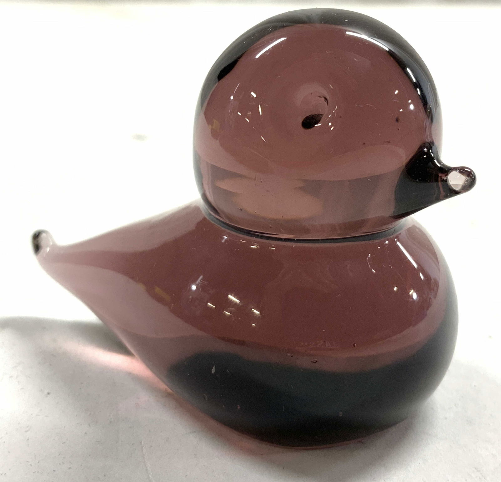 Art Glass Duck Figure Purple Paperweight: Figure depicts a duck. Piece is purple toned. Duck figure is glass. Piece measures approximately 2.5 inches deep 2 inches tall 1.5 inches wide. Paperweight, glass paperweight, art glass, glass duck, p