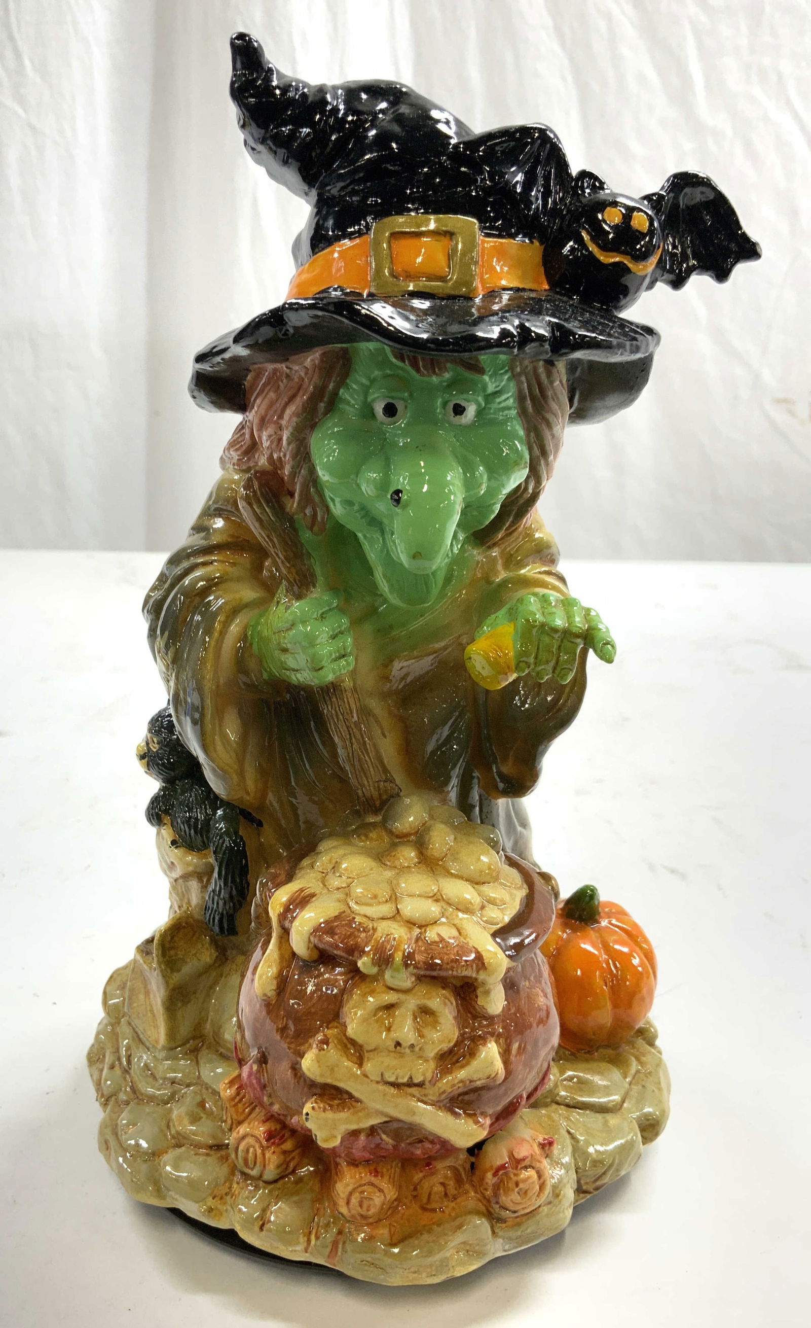 DEPT 56 Light Up Laughing Witch W Cauldron: Tag on underside reads DEPT 56. Piece depicts a witch with cauldron, pumpkin and black cat. Underside has on/off switch. Piece is plastic. Measures approx 9.5 inches tall 5 inches wide 5.5 inches deep