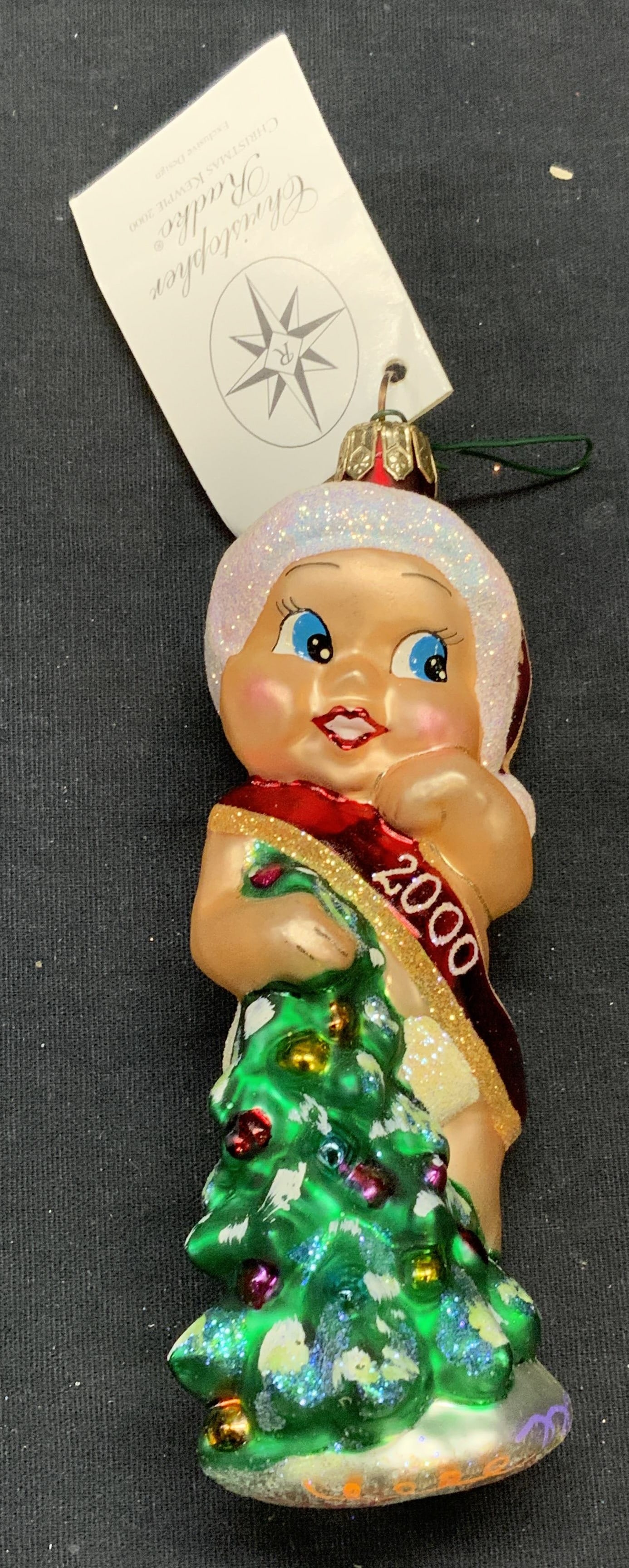 Christopher RADKO Glass Baby Ornament, 2000: Christopher RADKO Christmas Kewpie glass baby motif ornament. Produced 2000. Measures approx. 5 inches long. Includes original box. Some surface wear including scratching observed. Christopher RADKO, 