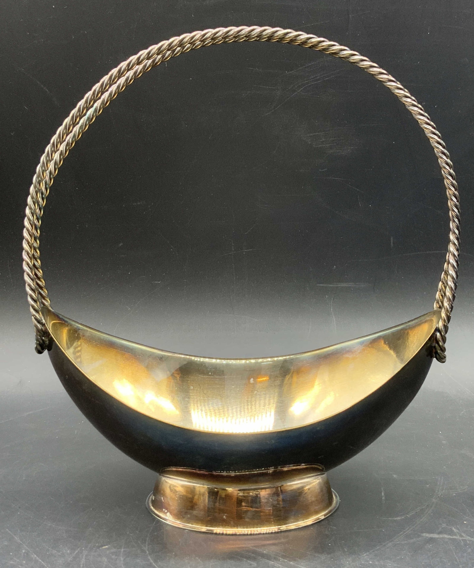Vtg Trademarked Silver Plated Twist Handle Basket: A vintage silver plated twist handle basket. Boat form. Trademarked on side and marked EP ON B. Measures approx. 7.75H x 6.75W in. Some surface wear consistent with age, use, and exposure. Some wear t