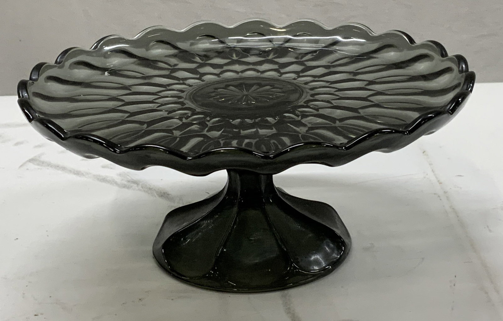 Vintage Black Glass Cake Stand: Vintage black glass cake stand. Molded geometric motif with scalloped edge. Measures approx. 10 x 4.5 inches. Some surface wear including scratching observed. Cake stand, black cake stand, glass cake 