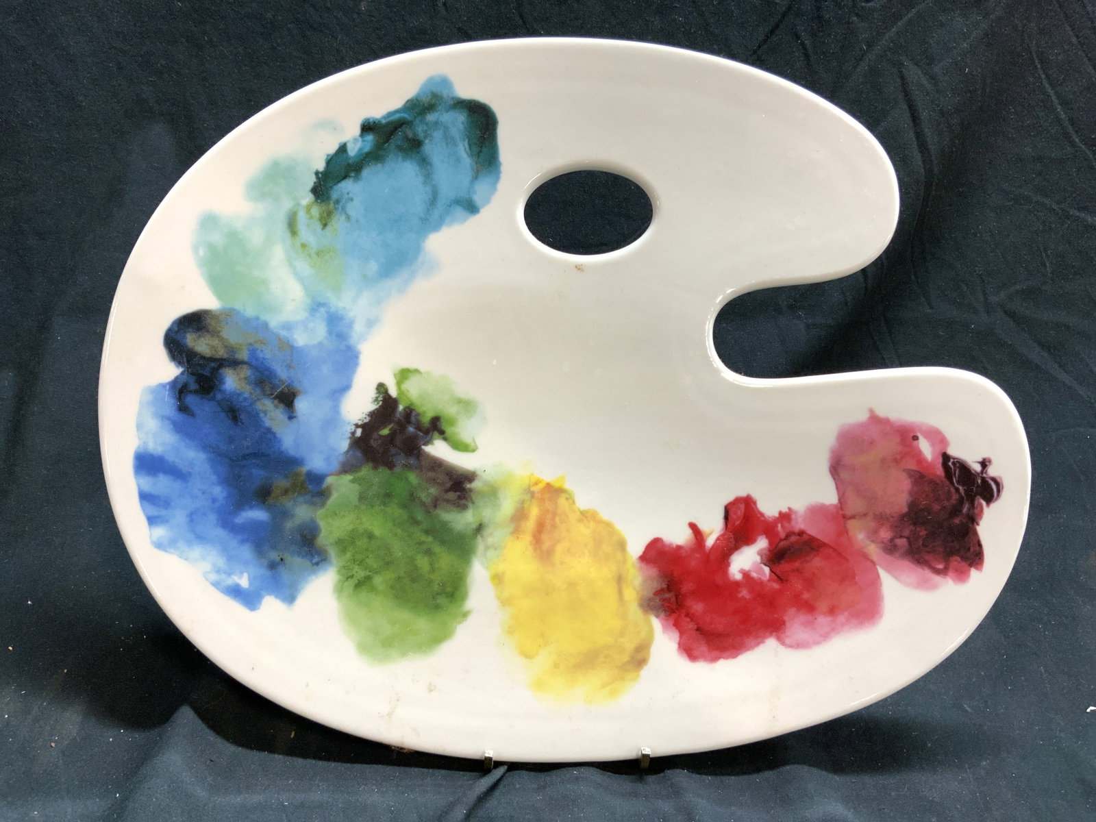 FISHS EDDY Porcelain Painting Palette Serving Dish: Underside is trademarked FISHS EDDY. Serving dish has shape of a painters palette with thumb hole. Piece has multiple tones to resemble painted splotches. Serving dish measures approximately 15 inches