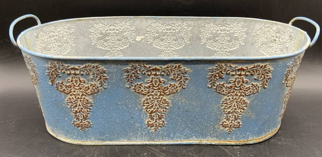 Vintage Metal Oval Form Outdoor Planter: A vintage oval form outdoor planter. Embossed metalwork designs. Primarily blue toned. Handles to either side. Measures approx. 5.5H x 14.5W in. Some discoloration, residue, and dents present.