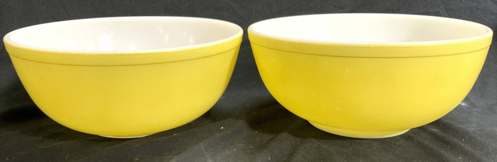 PYREX Pair Glass Serving Bowls Yellow: Undersides read PYREX. Lot includes 2 bowls. Each are yellow with white toned interiors. Rim exteriors have lips. Each vessel measures approximately 10.25 inches diameter. Bowls, serving bowls, Pyrex 
