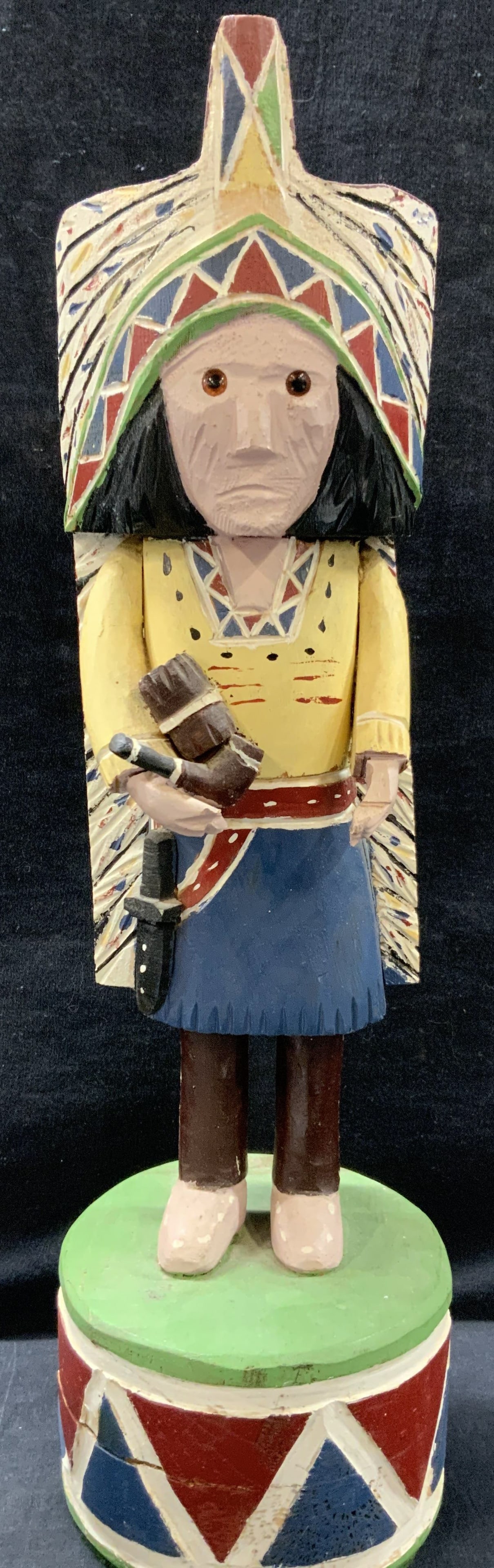 Hand Crafted Wooden Native American Figural: Marked in underside with sticker, artist, anonymous, hand carved and hand painted wood. Depicts a Native American Chief holding a pipe and a roll of cigars with a knife on his hip and hand painted hea