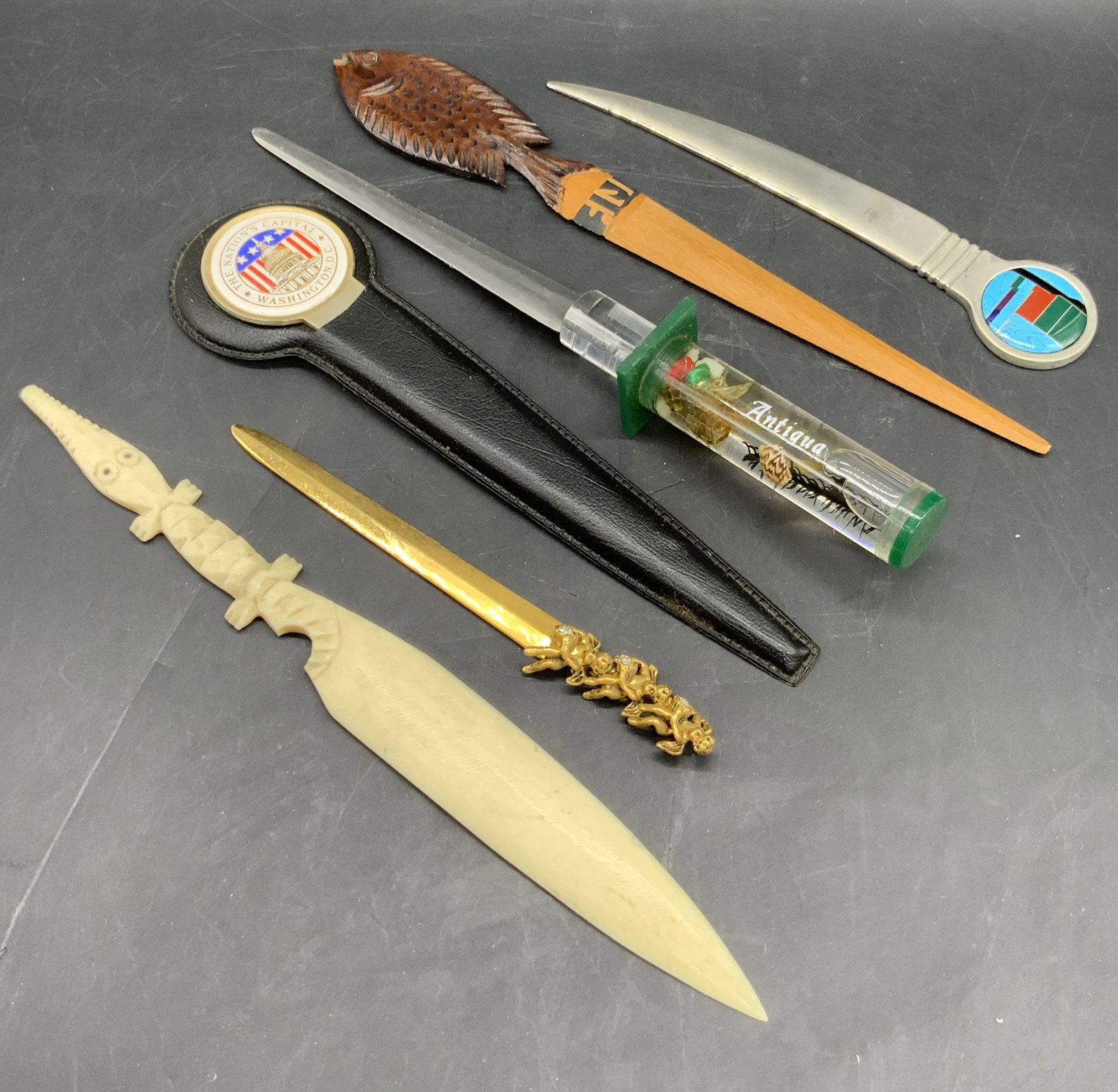 Lot 6 Metal, Wood, & Bone Letter Openers: Six metal, wood, and bone letter openers. Various shapes and sizes. Motifs include fish, putti, geometric designs, and more. Some pieces have faceted crystal accents, enamelwork, or stonework. Wooden 