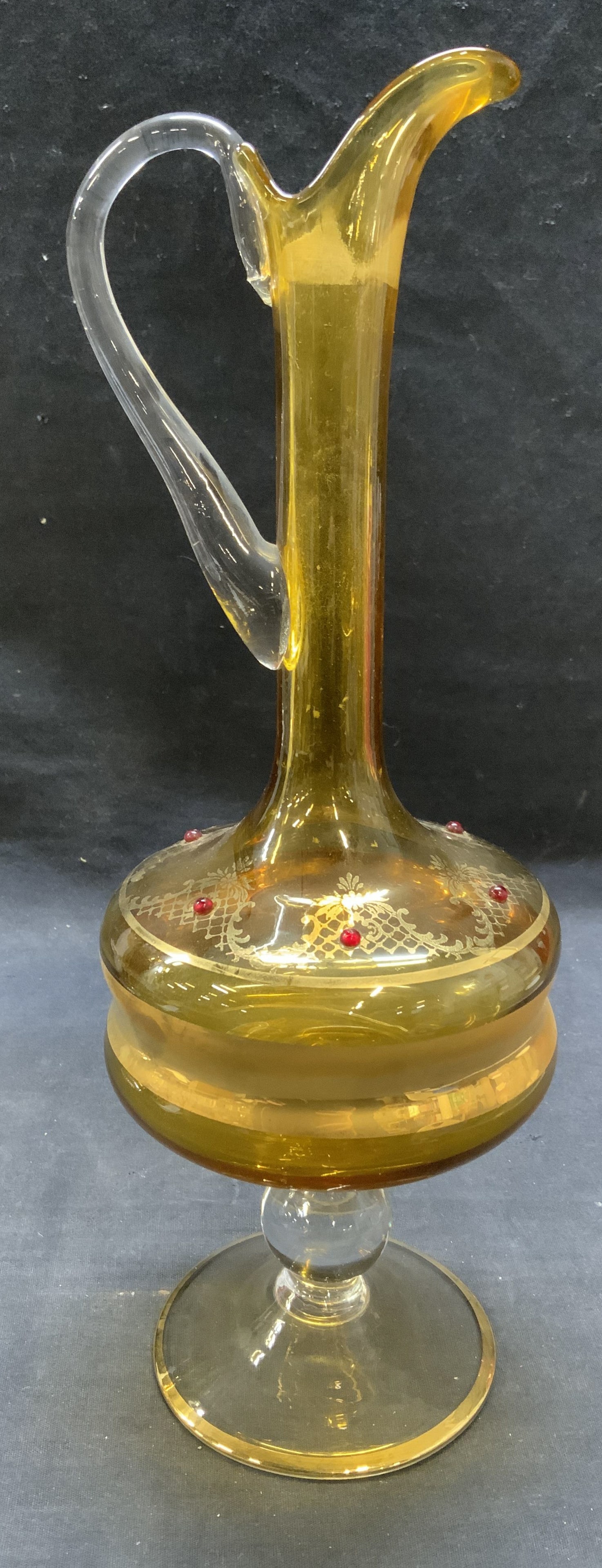 Vintage Gilt Amber Glass Ewer Pitcher: Vintage gilt hand blown amber glass Ewer pitcher with red cabochon decoration. Measures approx. 5 x 14 inches. Some surface wear including scratching and loss to gilt observed. Ewer, pitcher, glass Ew