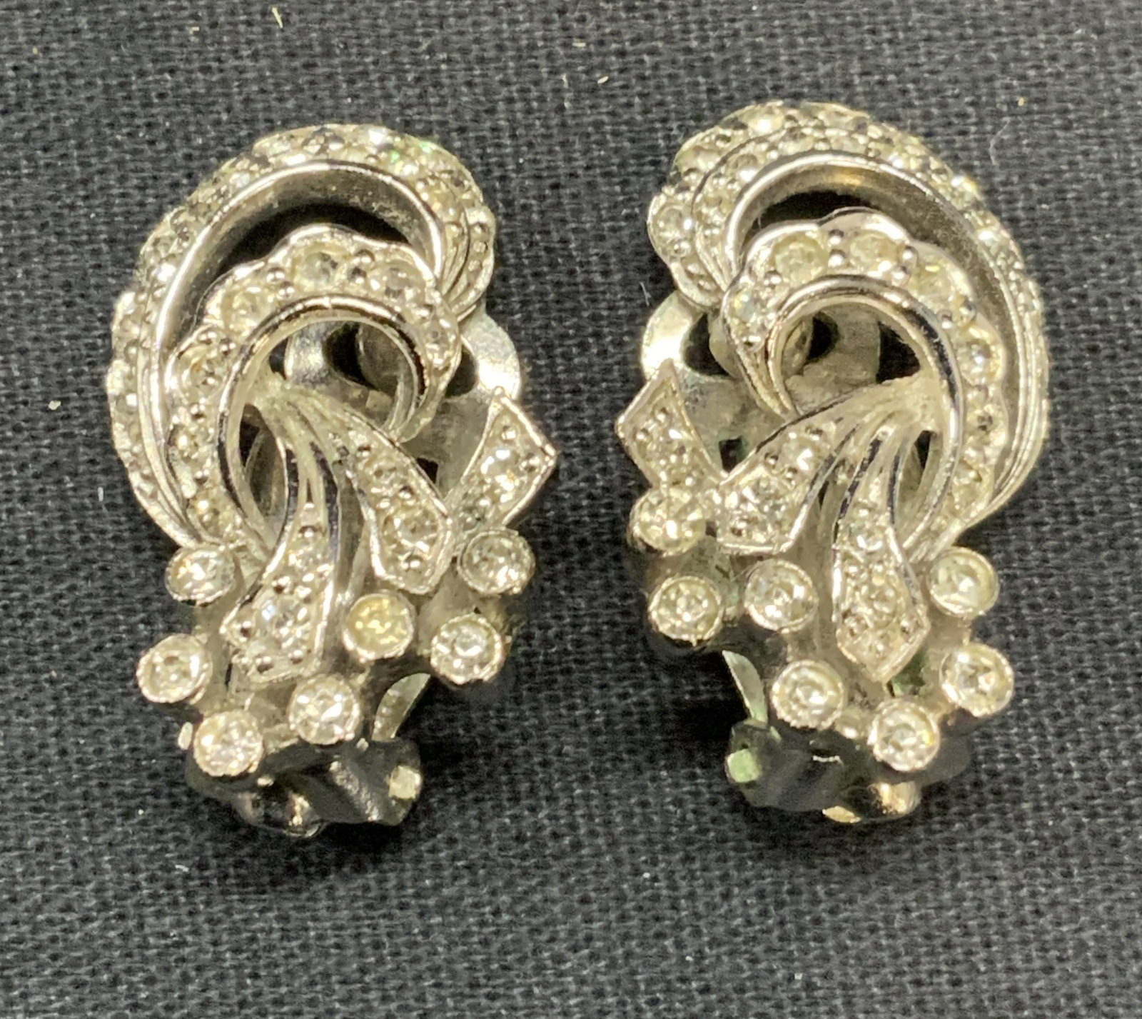 Vintage Pennino Silver Tone Crystal Earrings: Vintage Pennino silver tone and colorless crystal decorated clip on earrings. Signed to backing. Measure approx. 1 x .75 inches. Some surface wear including scratching observed. Estate jewelry, costum