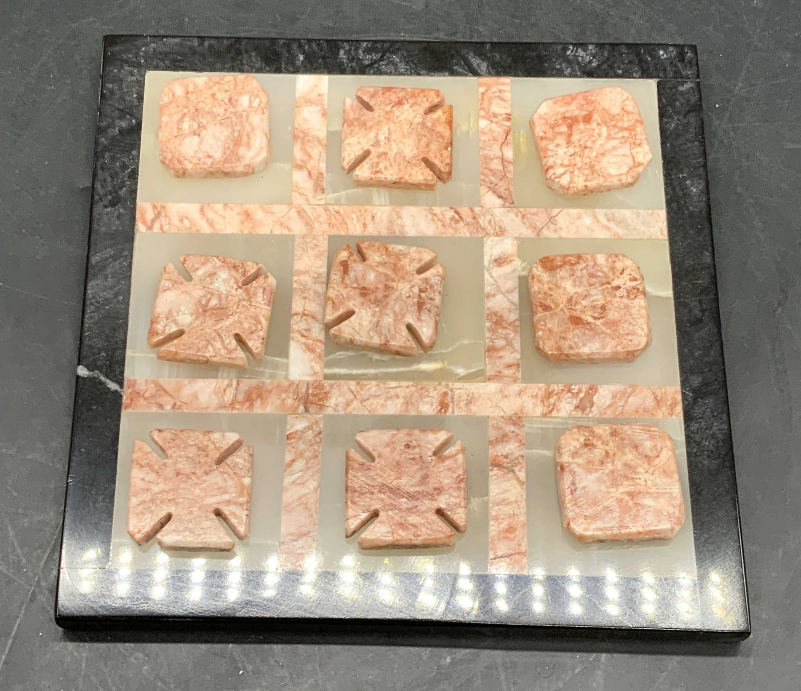 Set 10 Inlaid Natural Stone Game Board & Pieces: One natural stone game board with nine natural stone pieces. Polished, cut, and inlaid stonework designs. Stones are pink, white, or black hues. Game board measures approx. 7.25W x 7.25L in. Pieces ap