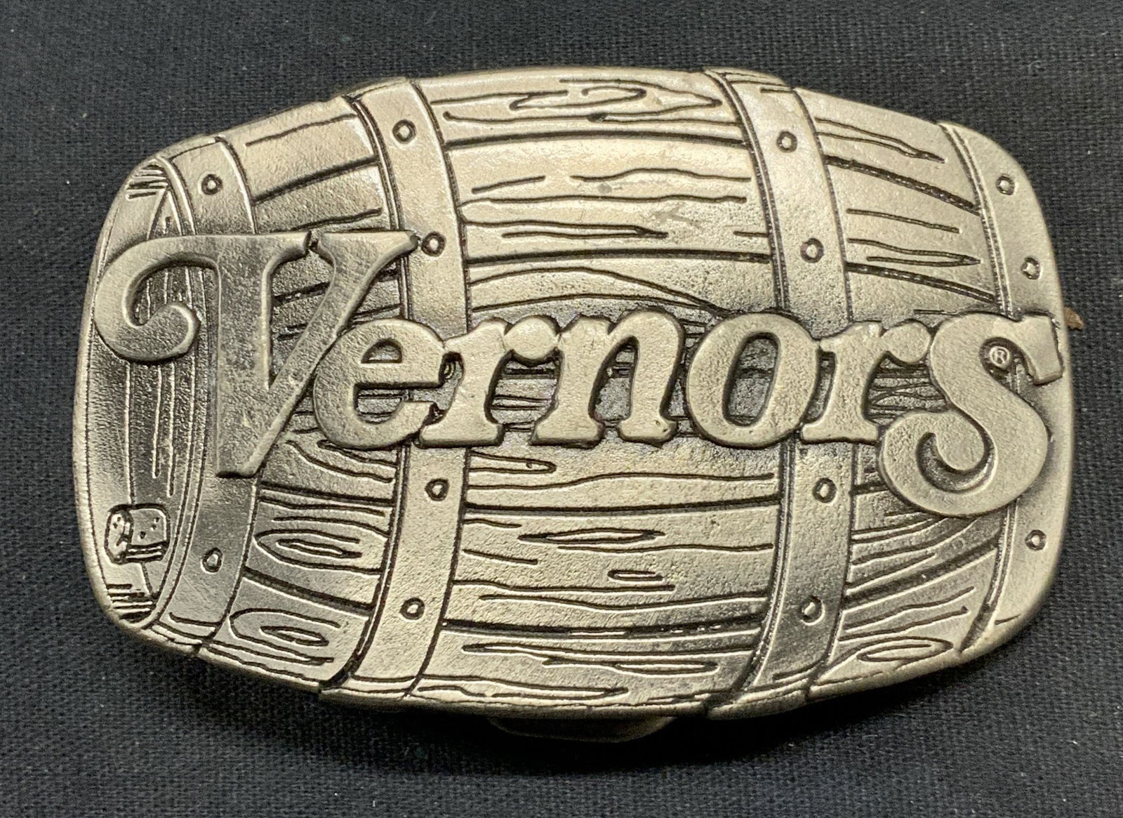 1976 Ltd Edt Vernors Barrel Belt Buckle: Vintage 1976 limited edition Vernors silver tone barrel motif belt buckle. Signed to underside. Piece has weight. Measures approx. 3 x 2 inches. Some surface wear including scratching observed. Vernor