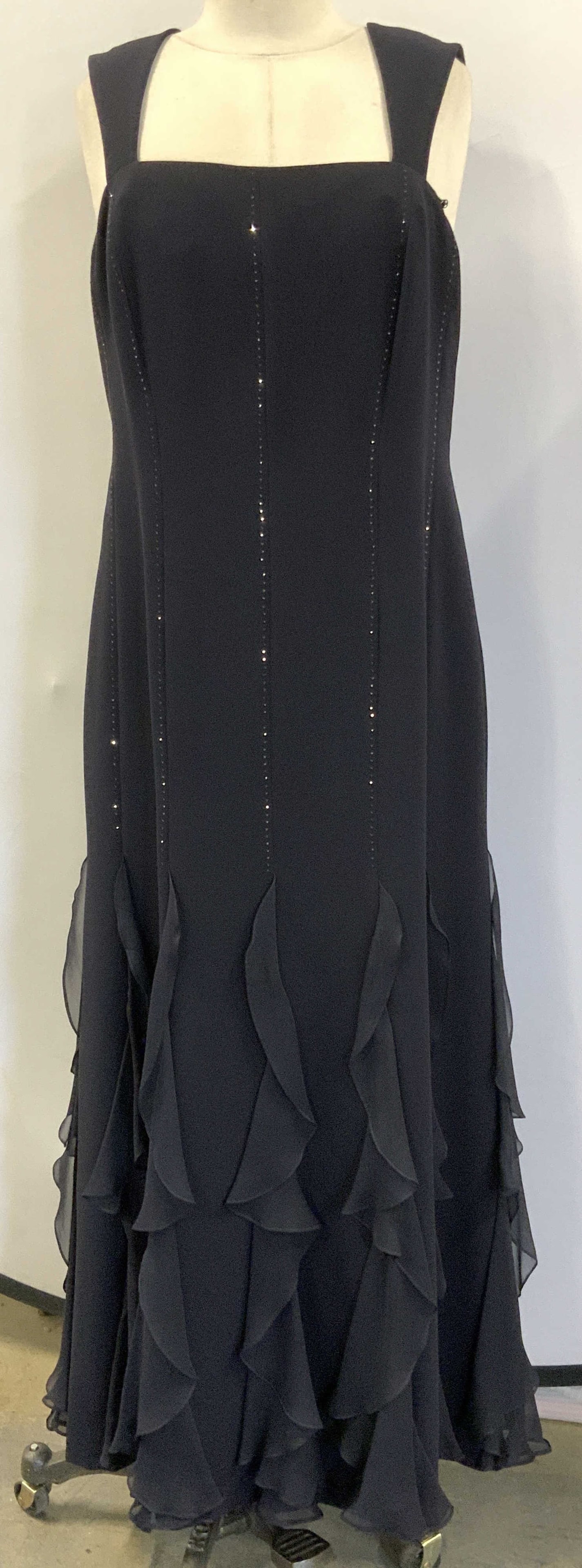 Sleeveless Evening Gown: A like- new evening dress in black with subtle sparkles and a Flowy hem with draped sheer ruffle design. No designer label. Dress size 32/34 in. Waist, 40 in. Hips, 52.5 in. Long. Fully lined. Evening