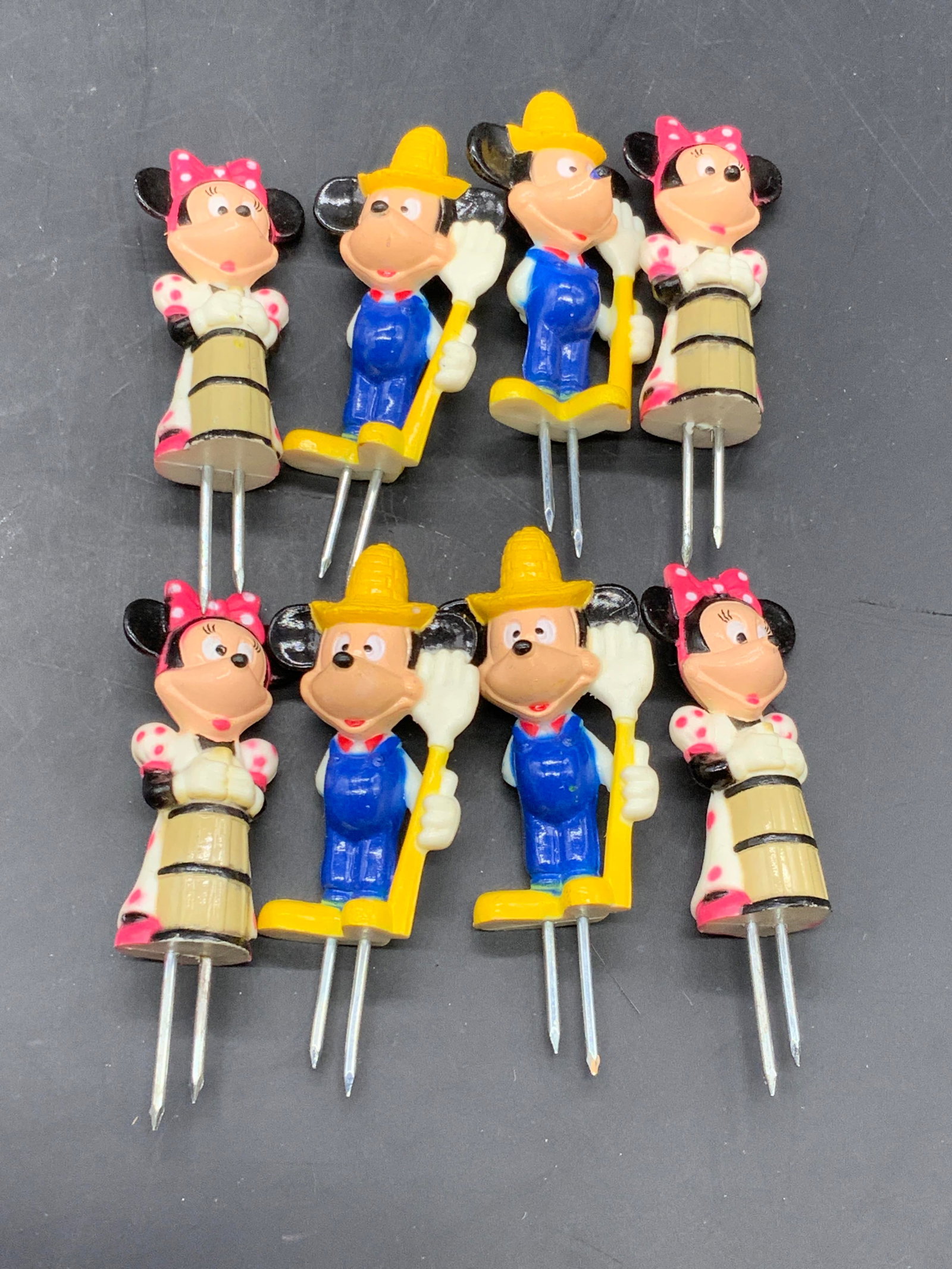Lot 8 DISNEY Mickey & Minnie Corn Holders / Picks: Disney Mickey & Minnie corn holders / picks. Reverse reads DISNEY. Pieces are similar in size. Minnie measures approx. 3L x 1W in. Crafted from composite and metal materials. Some surface wear consist