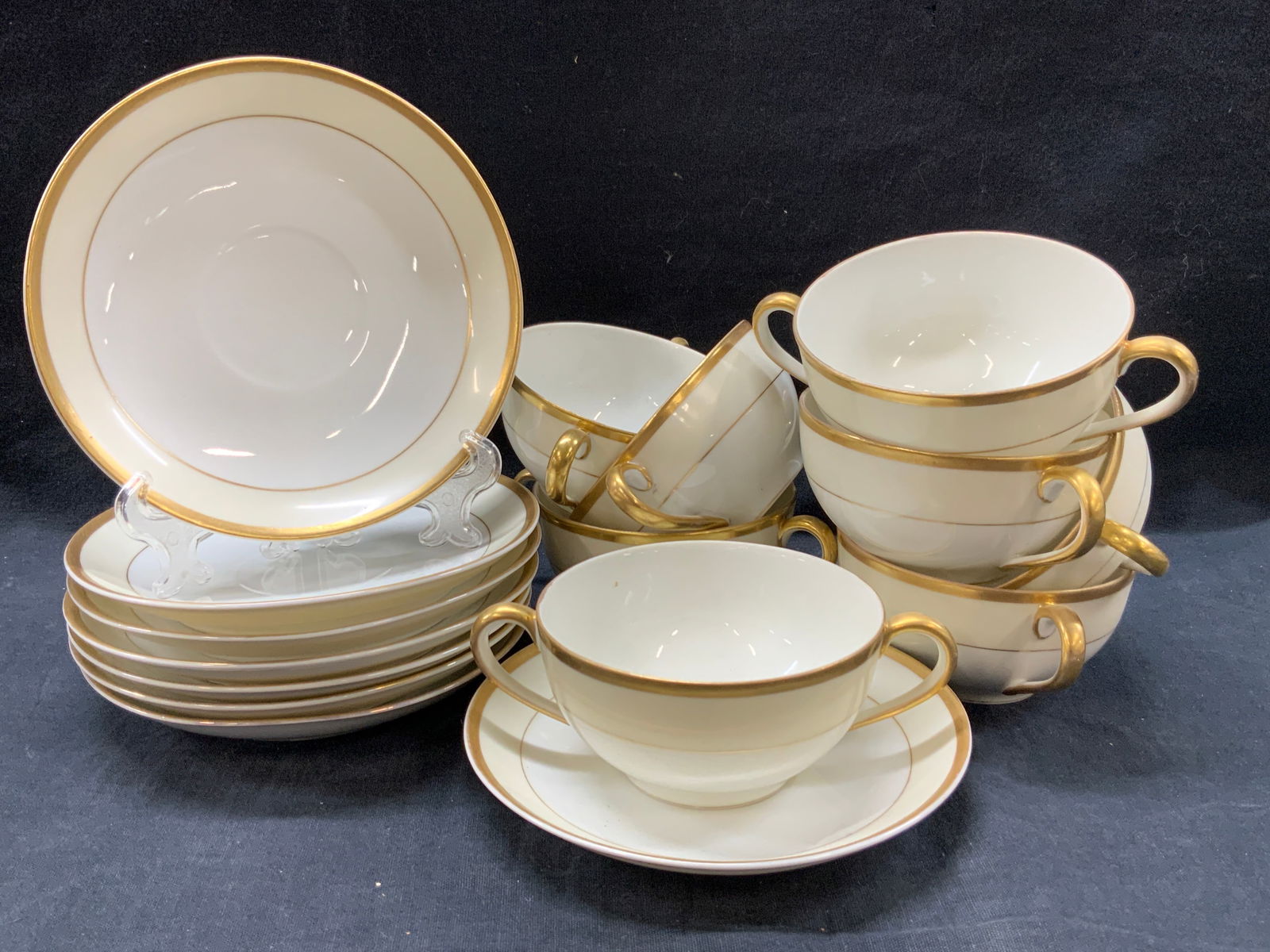 Set 16 NORITAKE Gilt Porcelain Cups & Saucers, JP: Set of 16 gilt porcelain cups and saucers marked NORITAKE, Japan on underside. Off white with gilt rims and side handles. 8 cups and 8 saucers at 5.5 Inch diameter. Moderate surface wearing due to age