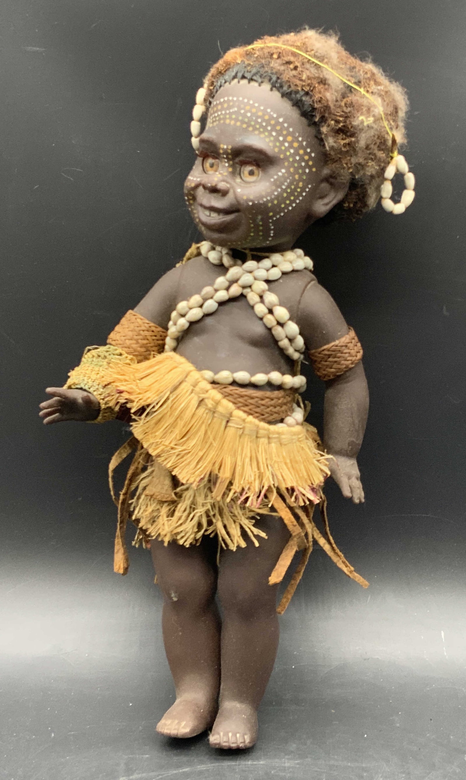 MATTI AUSTRALIA Hand Painted Doll Figural: A composite hand painted MATTI AUSTRALIA doll figural with articulated limbs. Clothing and accessories crafted from shell and natural materials. Measures approx. 13L x 6W in. Measured at widest point.