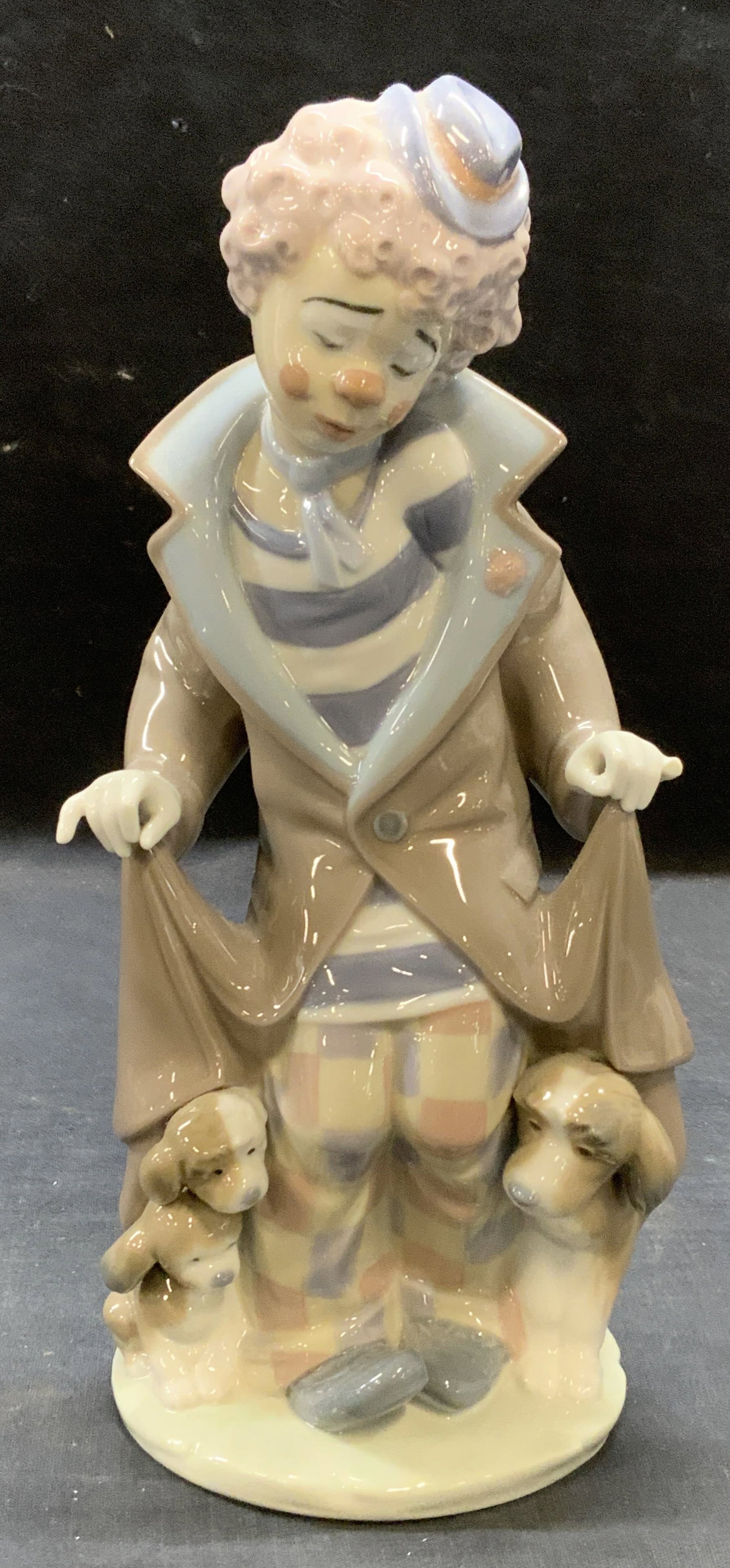 Lladro Porcelain Clown Figural, Spain: Lladro porcelain clown figural in brown and blue. Trademarked to underside. Made in Spain. Measures approx. 4.5 inches wide and 9.5 inches tall. Some surface wear including small chip observed. Lladro