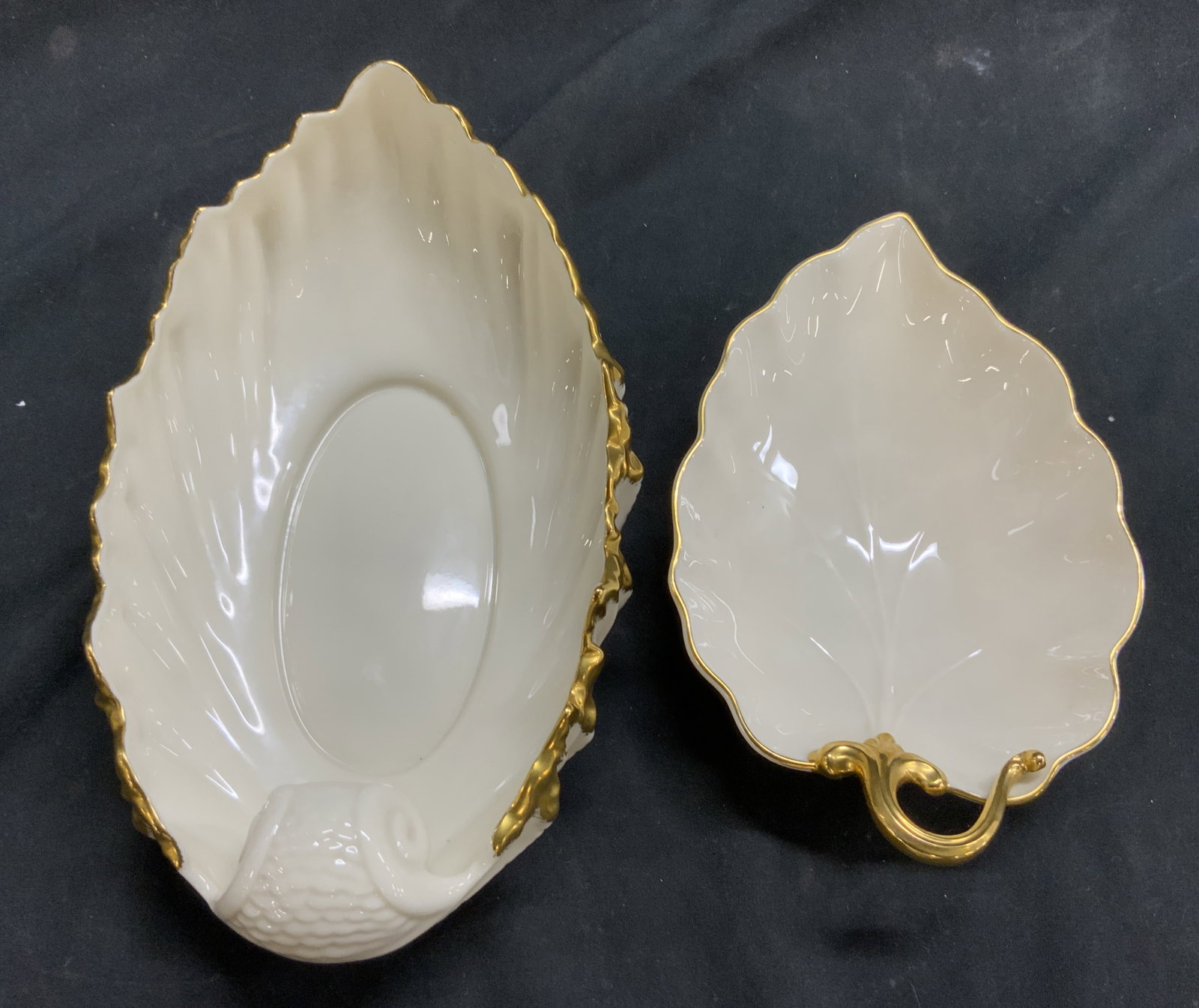 LENOX Lot 2 Porcelain Leaf Dishes: Undersides of each dish is marked LENOX. Each piece is cream toned with gilt rims. Each vessel is porcelain Largest dish measures approx 9 inches long 5.25 inches wide 3 inches tall. Lenox porcelain, 