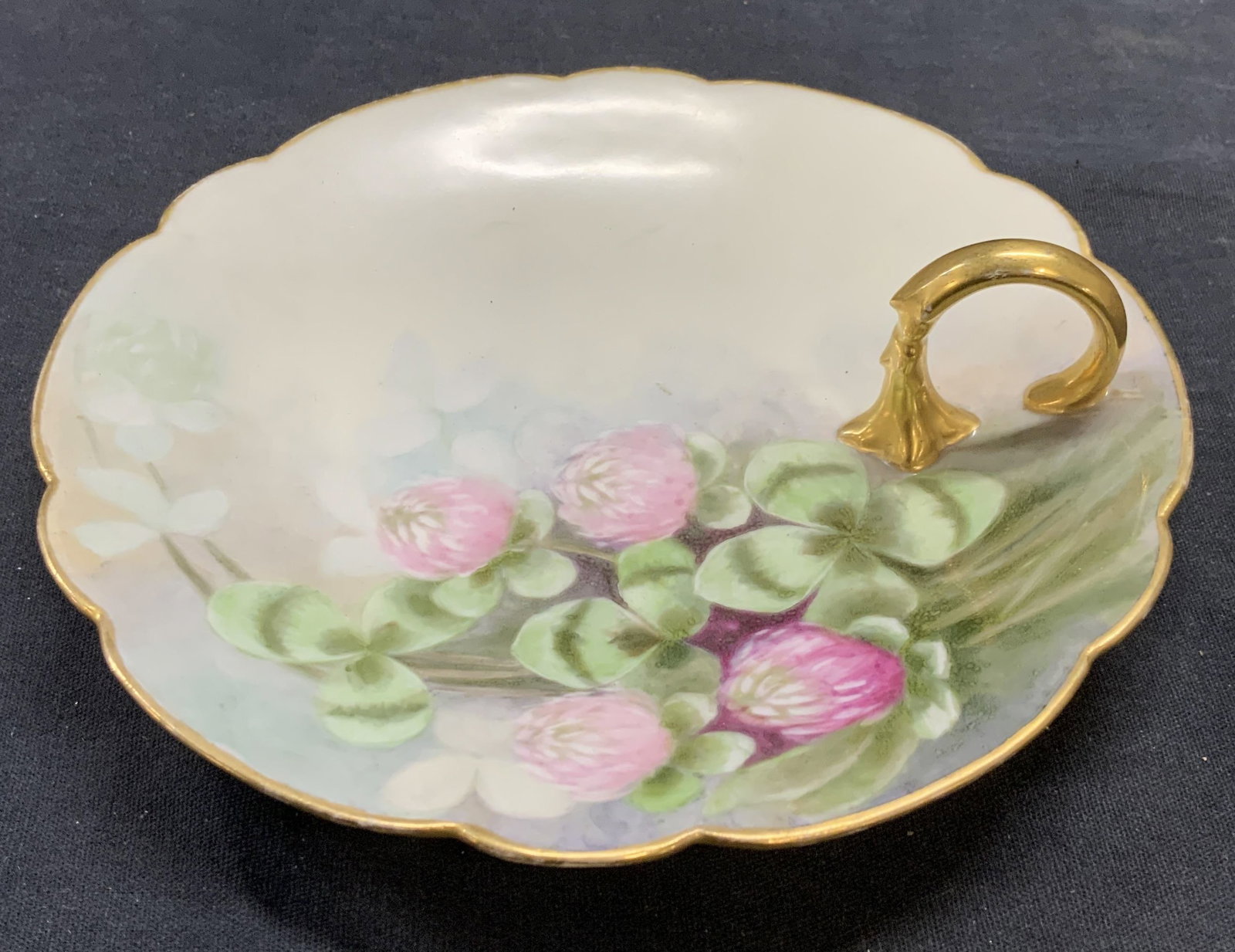 Vtg PL Limoges France Porcelain Dish: Vintage PL Limoges porcelain dish with hand painted floral motif and gilt handle. Trademarked to underside. Made in France. Measures approx. 6.5 inches wide. Some surface wear including scratching obs