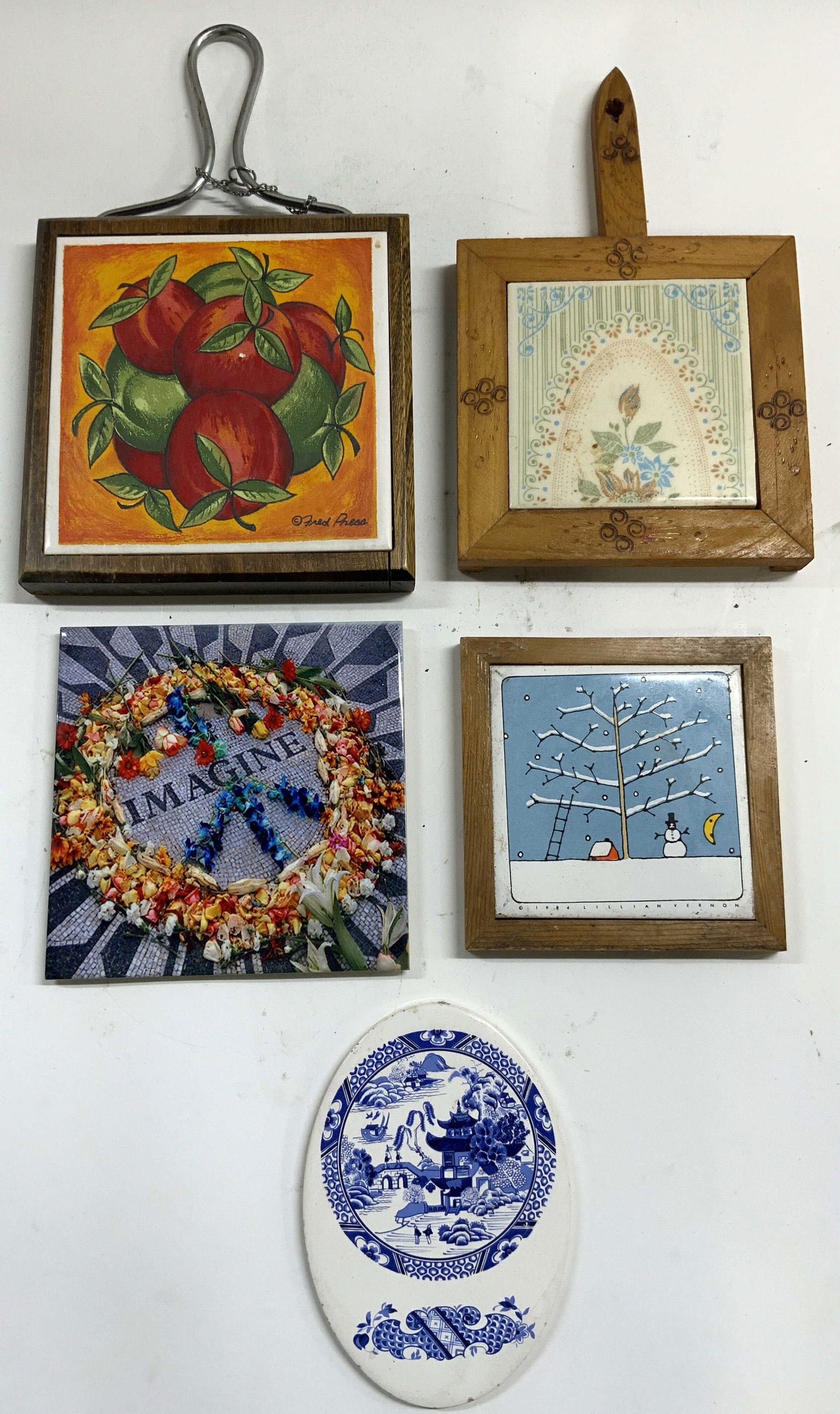 5 Wood & Porcel Trivets, Lillian Vernon Dal Tile +: Lot includes 1 trivet with metal handle, wood border and porcelain center with apple detail trademarked FRED PRESS, 1 trivet with wood hand and border with porcelain tile center, 1 porcelain tile triv