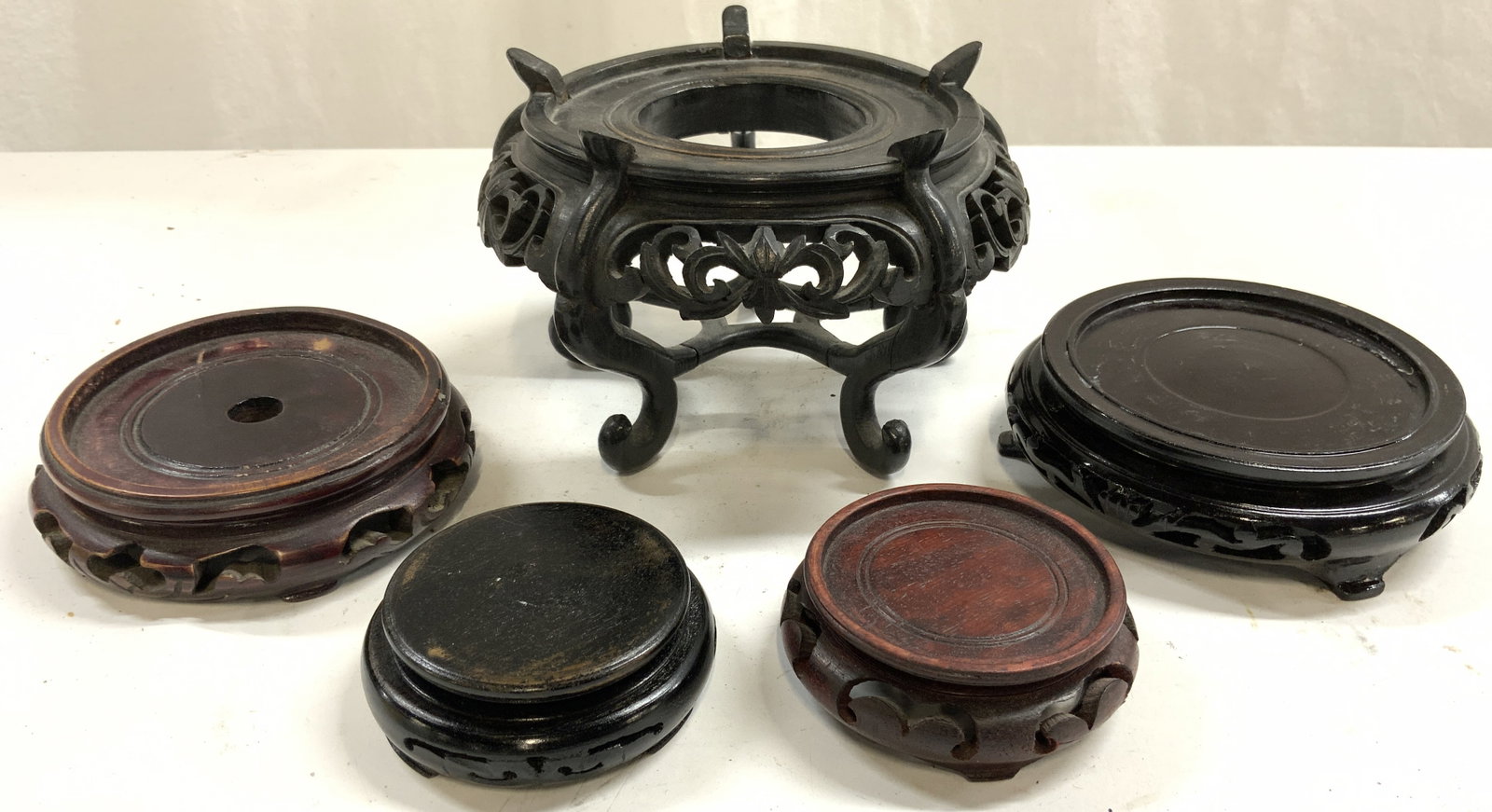 Lot 5 Carved Asian Wooden Stands: Lot include 5 stands. Each ware carved wood. Some black, some mahogany toned, some brown toned. Each piece is footed. Largest stand has 5 curled feet. Measures approximately 6 inches wide, 4 inches ta