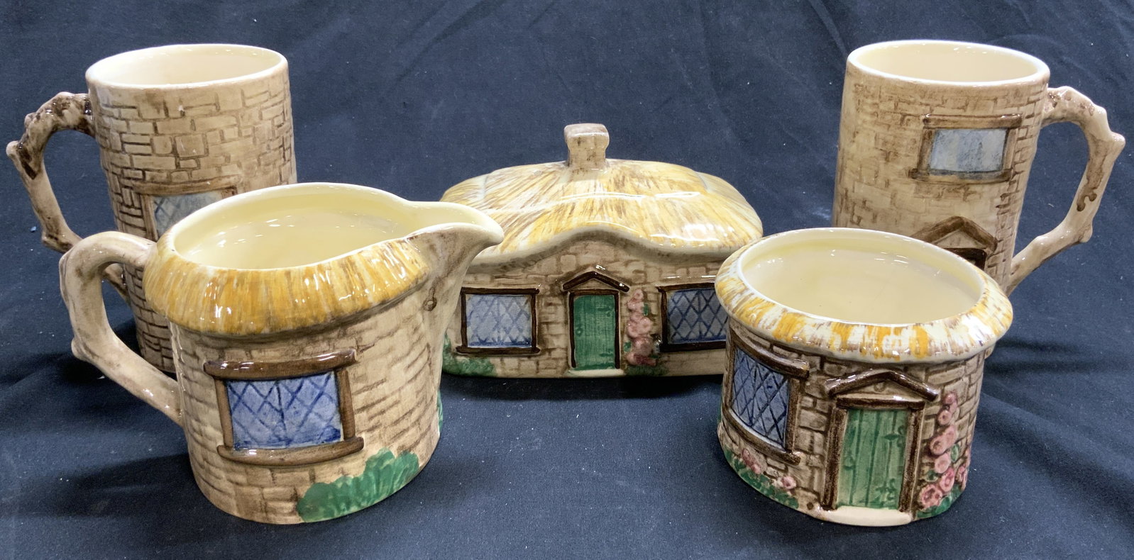 STAFFORDSHIRE CROFT Handcrafted Set 5 Cottageware: Undersides are marked STAFFORDSHIRE CROFT HAND MADE AND HAND PAINTED ENGLAND. Lot includes 2 mugs, 1 creamer dish, 1 sugar dish & 1 lid. Each piece has cottage house detail. Each mug measures approxim