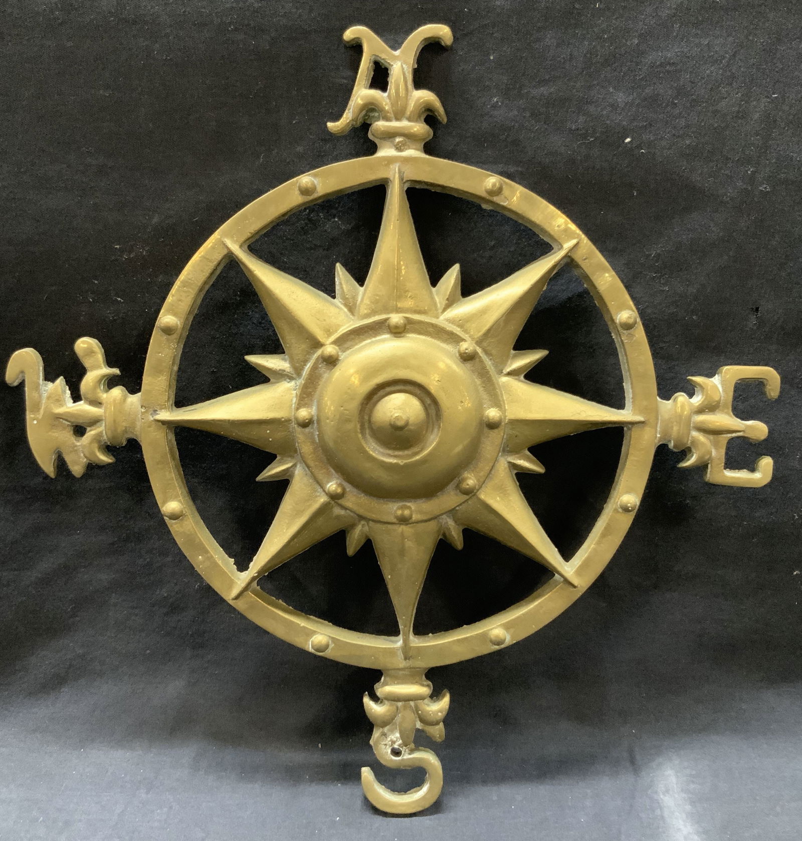 Cast Brass Coastal Directional Wall Ornament: Cast brass, weighted coastal directional wall ornament, with North south East and west with a nautical compass Star in the center. Approximately 13 x 13 inches Moderate wearing to brass due to age and