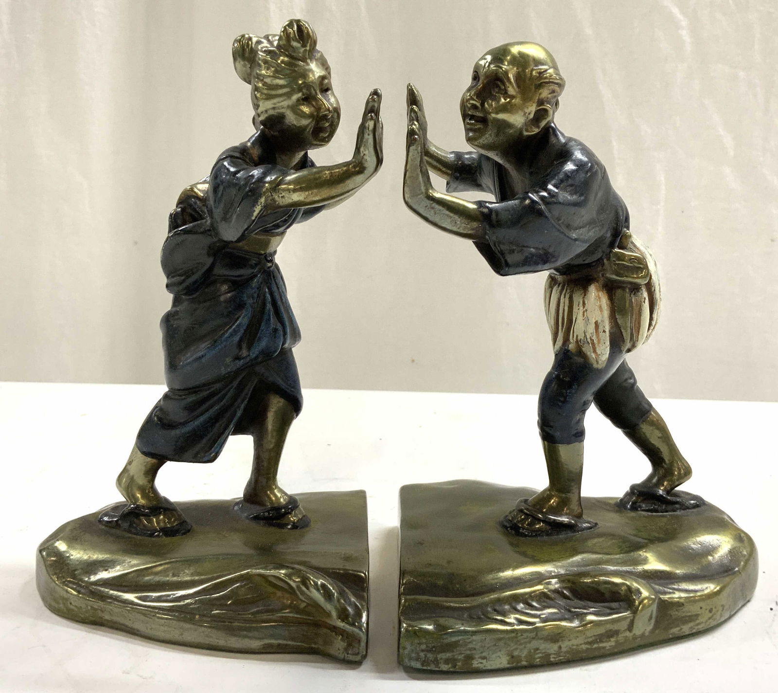 Bronze Polychrome Bookends Male & Female Figures: Lot includes 2 bookends, one male & 1 female figure. Each piece is bronze polychrome. Depicts figures pushing in between objects together. Bookends each measure approx 7.5 inches tall 5 inches deep 4.