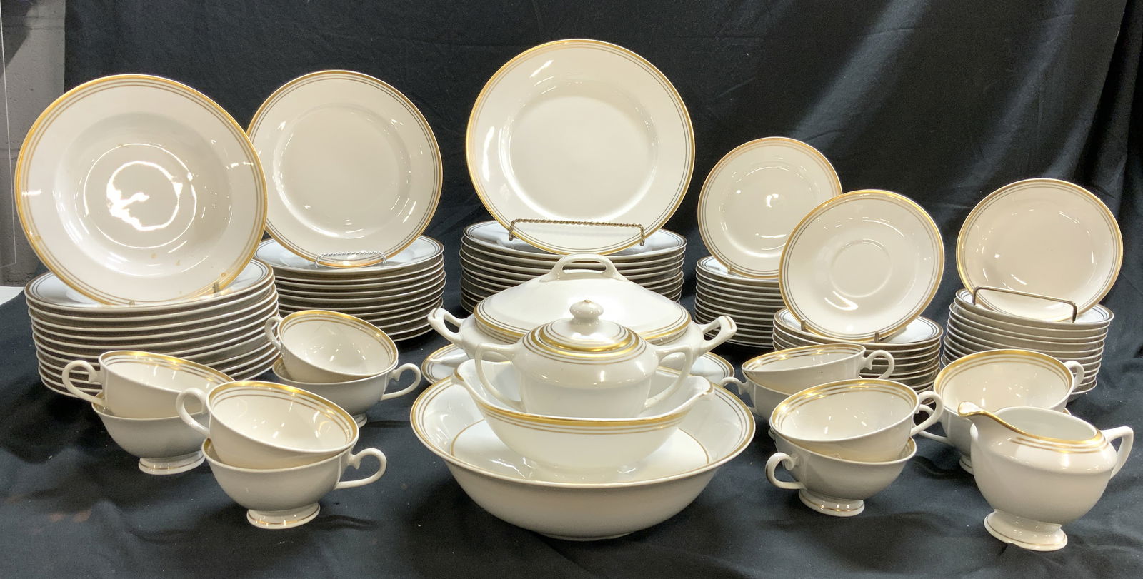MARY TARSHES Set 89 Gilt Rim Porcelainware USA: Undersides are marked MARY TARSHES USA. Lot includes 12 dinner plates, 12 bowls, 12 salad plates, 12 bread plates, 12 small bowls, 12 teacups, 11 saucers, 1 lidded serving dish with handles, 1 oval se