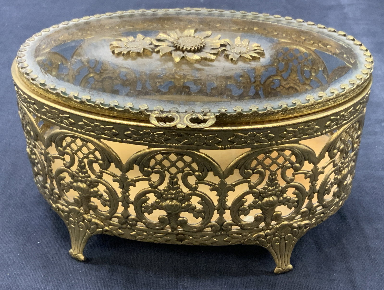 Vtg Embossed Gold Tn Trinket Box: Vintage gold toned metal possibly brass embossed framed dresser Trinket box/ jewelry box with glass lid with carved sun flowers made of brass on lid. Body of box has cut outs and embossing of intricat