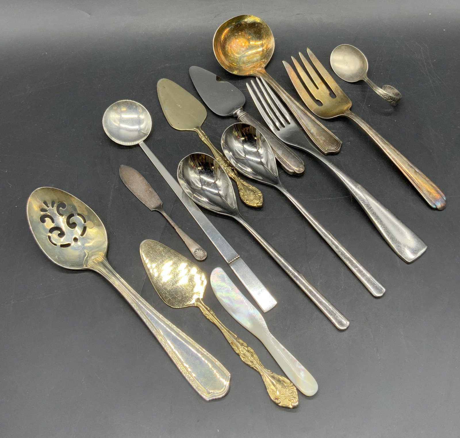 Lot 13 Silverware, Wedgwood, Waterford & More: A group lot of thirteen pieces of silverware. Spoons, serving pieces, forks, and more. Pieces are crafted from stainless, silver plate, mother of pearl, and metal. Brands include Waterford, Wedgwood, 