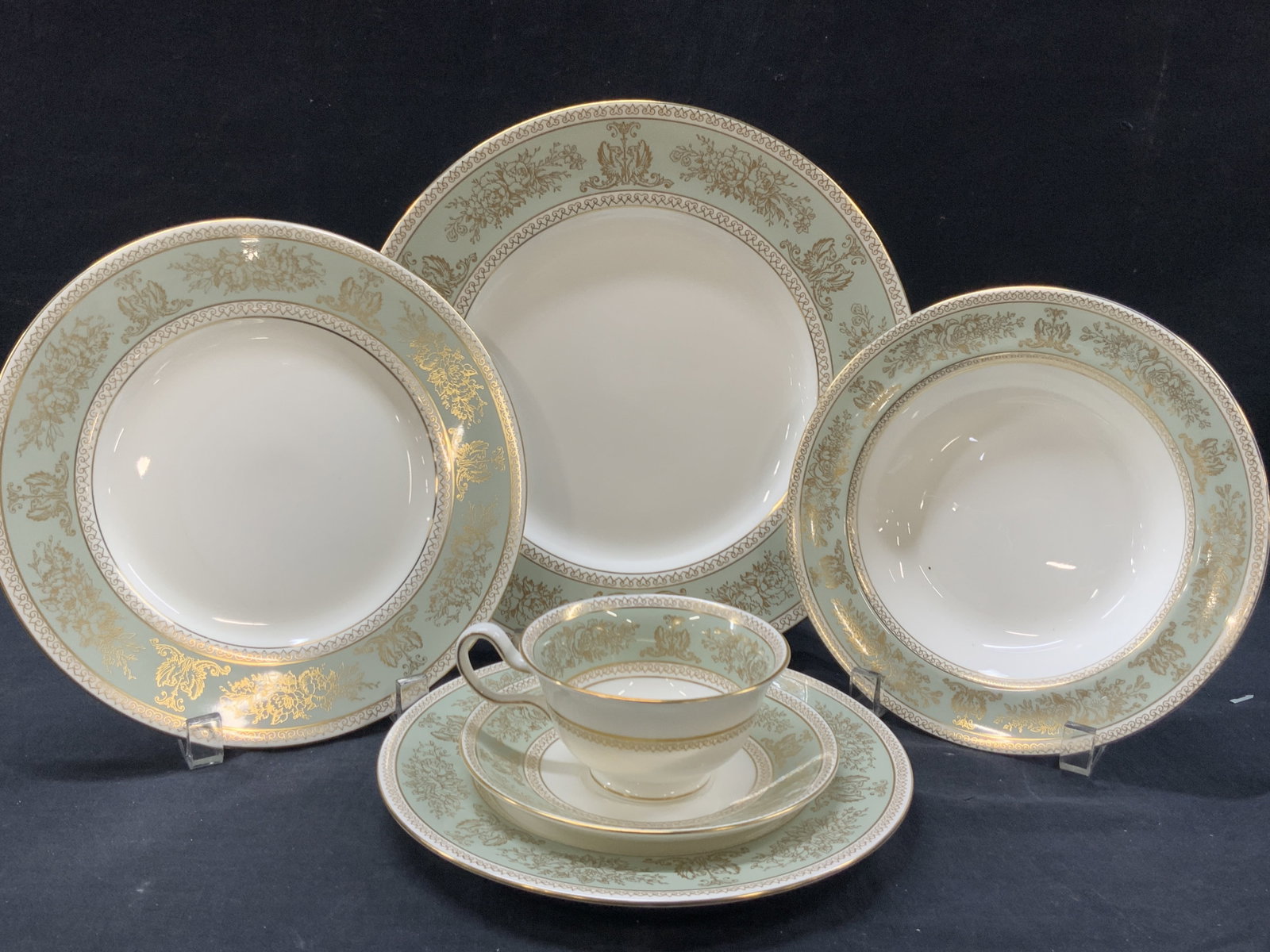 Set 45 Wedgwood Gilt Bone China Dishes, England: Set of 45 Wedgwood bone China dishes, made in England in the gold Columbia style with gilt rims and ornate designs in gold against a light green band on edges of dishes and cups. 8 entry dishes at 11 