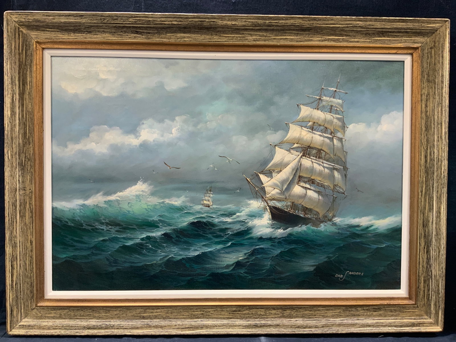 Bob Sanders Sgd Maritime Oil Painting 43in: Signed Bob sanders on right corner. Oil painting that depicts various ships on the crashing sea. Framed in a light and dark speckled wooden frame. Approximately 31 x 43 inches window measures 23 x 35 