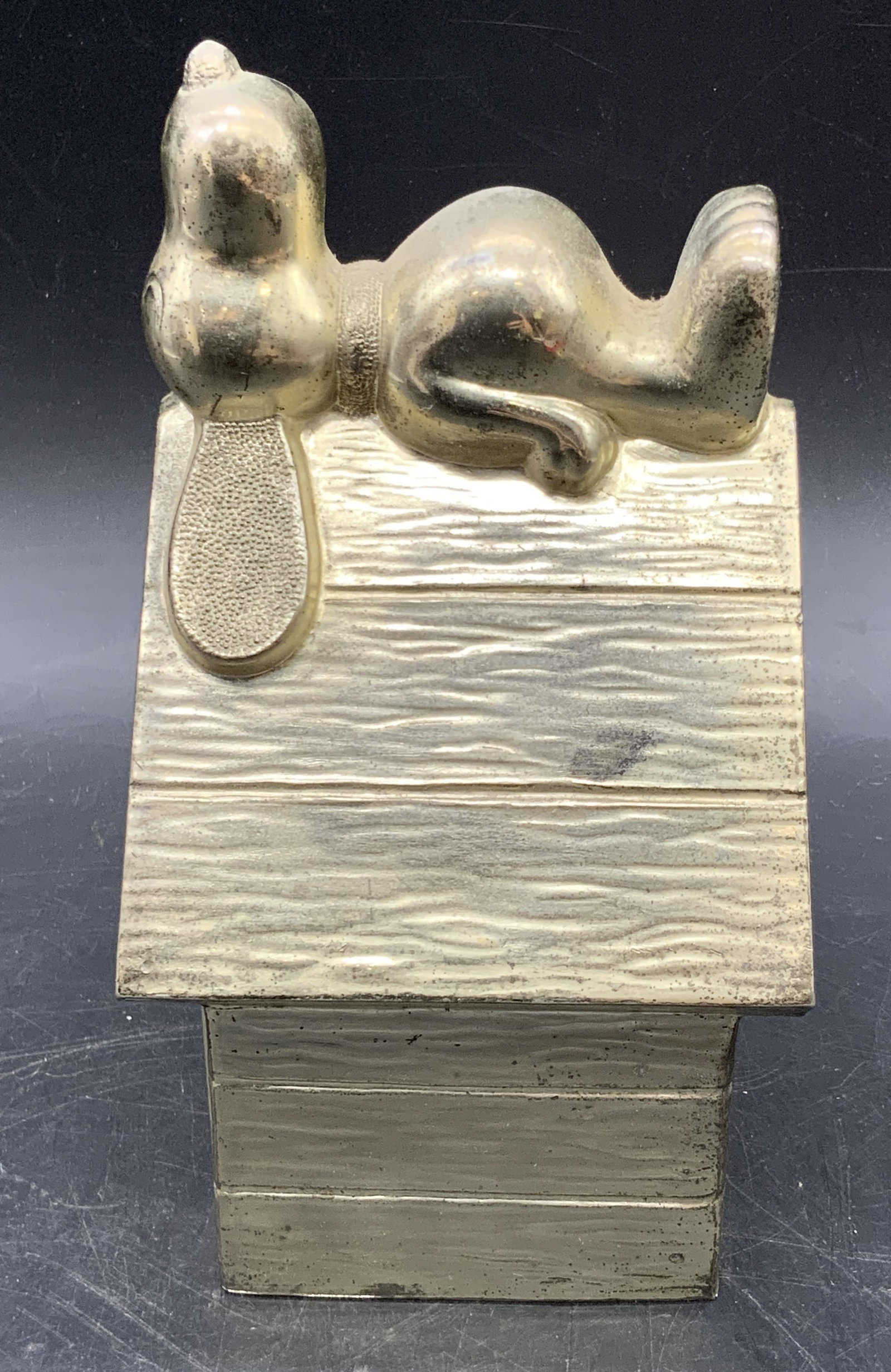 1966 Snoopy On House Silver Plated Coin Bank: A vintage silver plated coin bank featuring Snoopy, from The Peanuts, sleeping atop his doghouse. Underside marked LEONARD SILVERPLATE, SNOOPY, UNITED FEATURE SYNDICATE. Dates to underside read 1958 a