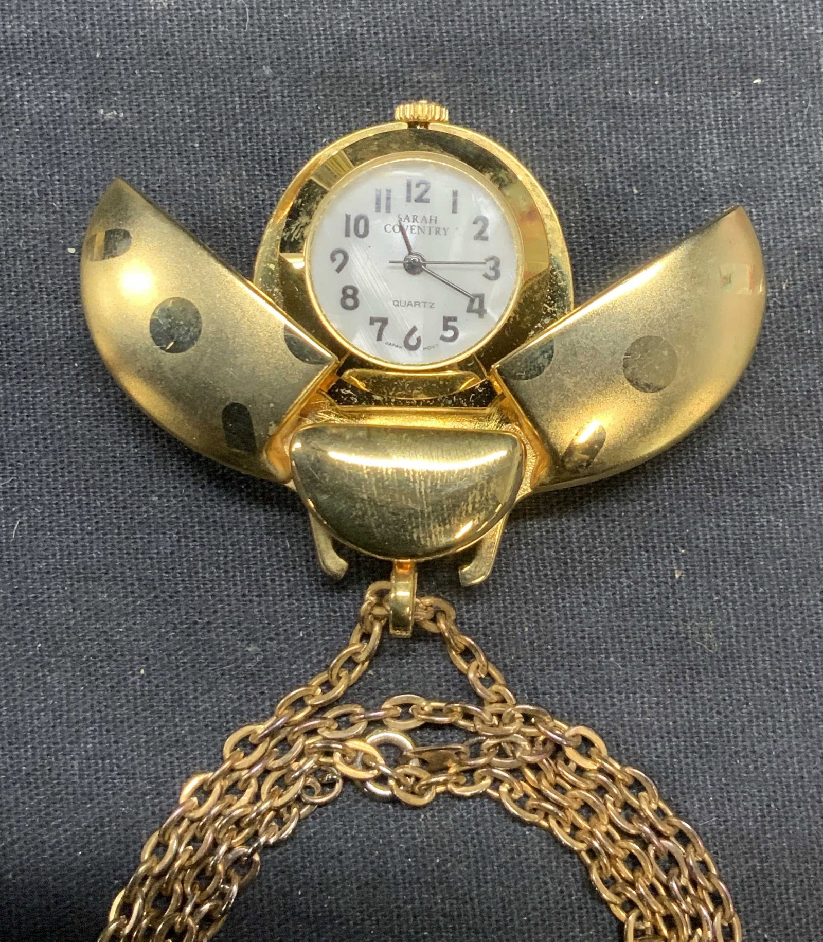 Sarah Coventry Gold Tn Ladybug Watch Necklace: Vintage Sarah Coventry gold tone Watch pendant necklace. Ladybug form watch pendant with articulated wings. Signed on watch face. Drop length approx. 15 inches. Pendant measures approx. 1.5 x 1 inches