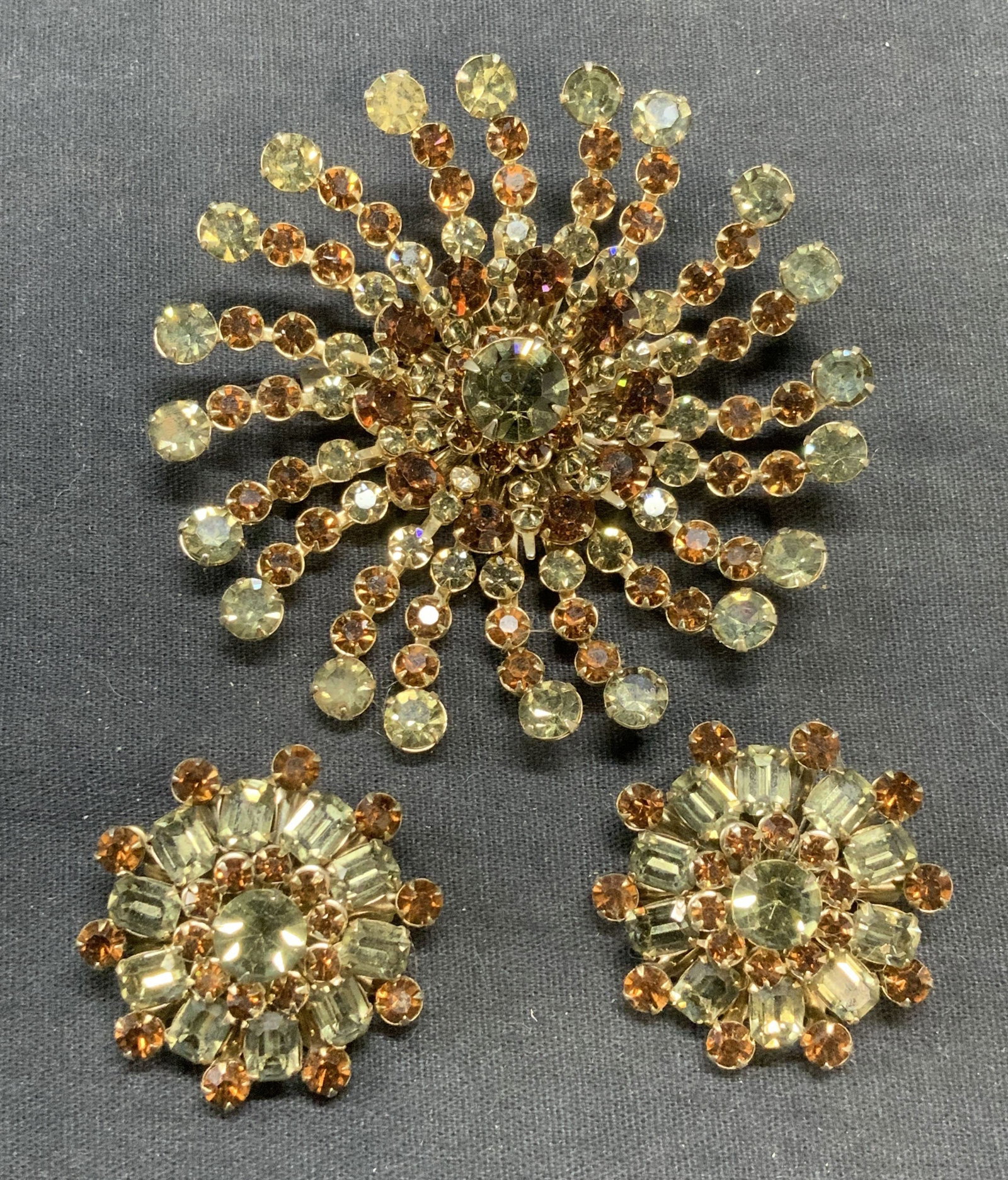 2 Vtg Gold Tn Green Crystal Brooch & Earrings: Lot of 2 pieces vintage gold tone green and brown crystal decorated brooch and matching earrings. Hinge pin to brooch. Clip on earrings. Brooch measures approx. 3 inches wide. Earrings measure approx.
