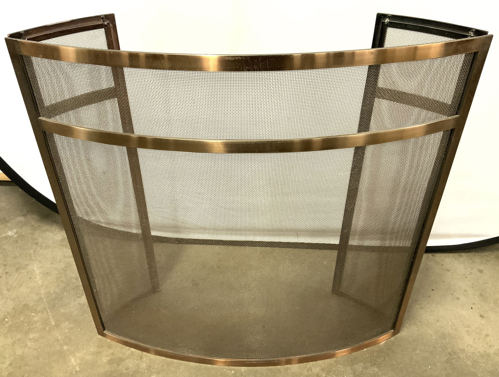 Folding Brushed Metal Curved Fireplace Screen: Fireplace screen is brushed metal. Piece is copper toned. Fireplace screen has curved structure with 2 areas which fold at ends. Piece has black toned screen/netting area. Piece measures approximately