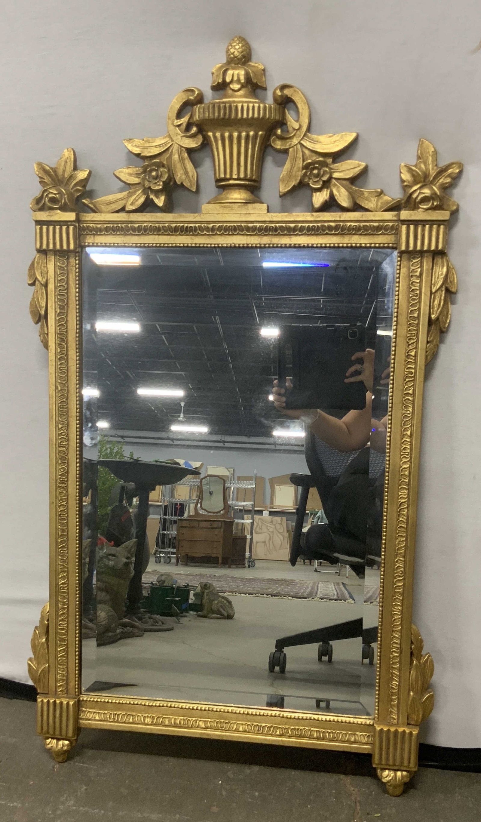 FB DECORATIVE ARTS INC Gilt Wood Beveled Mirror: A gilt wood beveled mirror. Floral and foliage motif to the design. Sticker to reverse reads FB DECORATIVE ARTS INC. Measures approx. 46.25L x 26W in. Metal hardware to the reverse for display. Some s