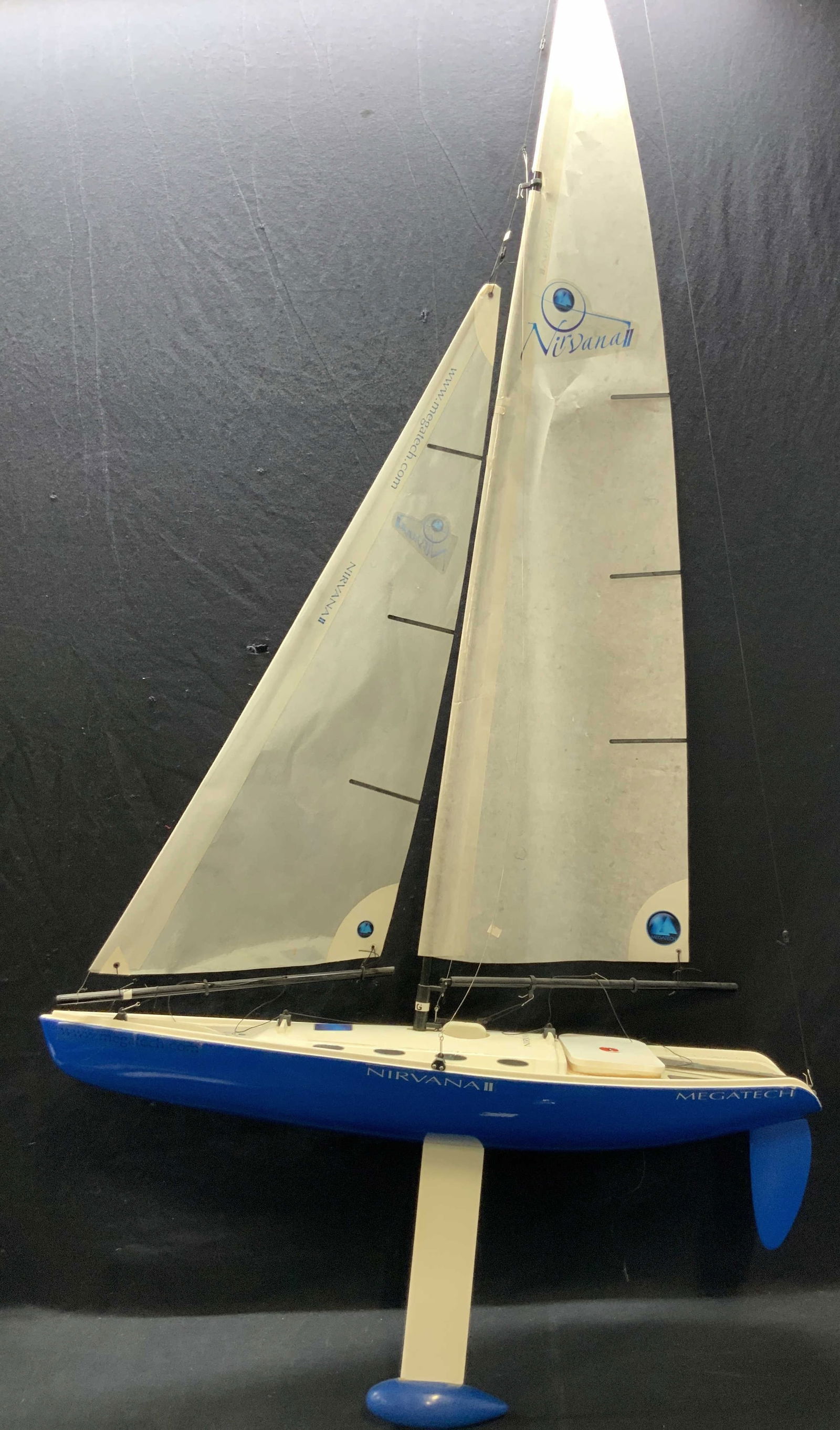 Nirvana II Megatech RC Sail Boat 63inH: Approx 63 inches in total height and 31 inches long and 8 inches wide. RC blue tones hard composite crated sail boat with underside rudder and parchment paper made sails, marked Megatech on sides. Mod