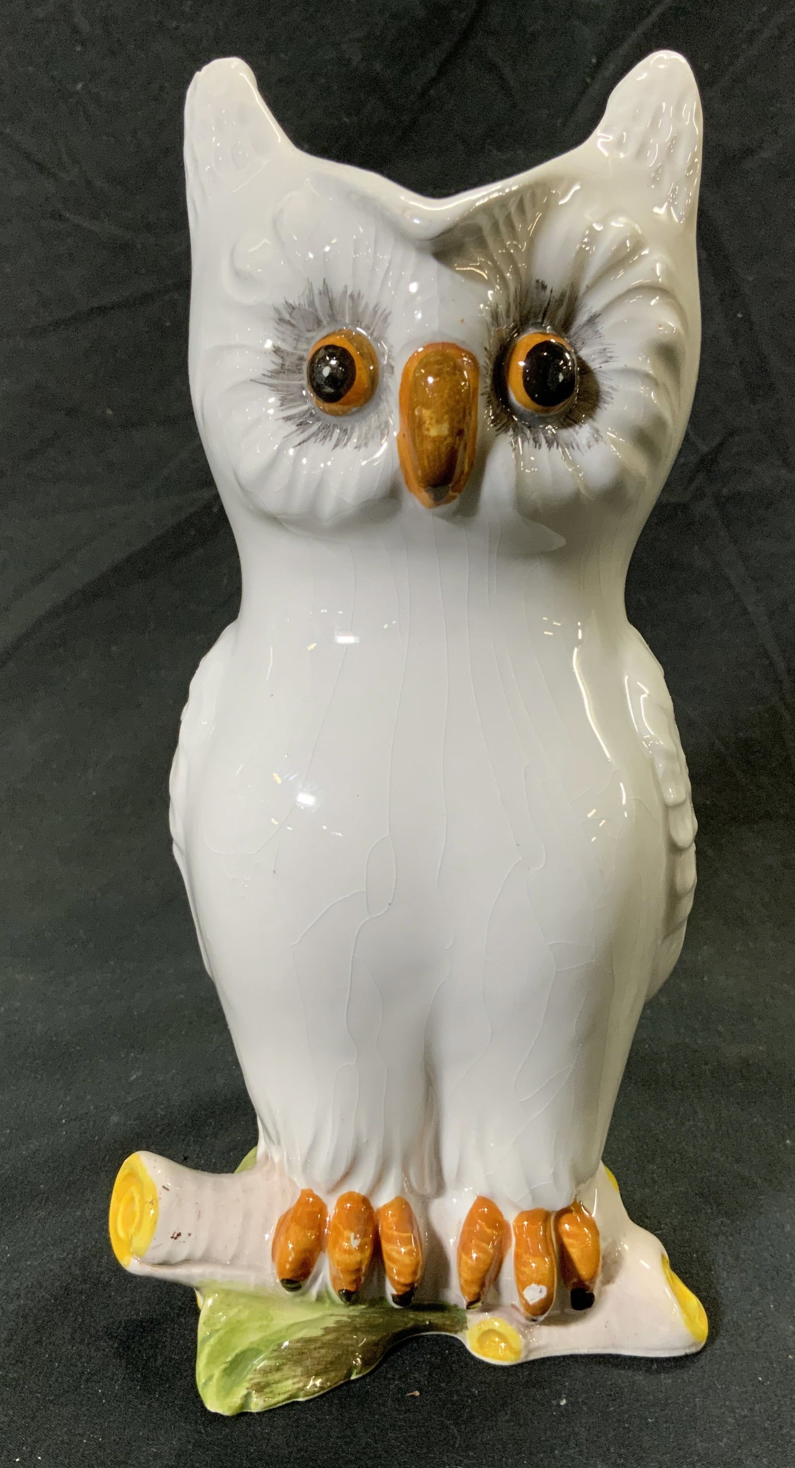 Painted Porcelain Owl Pitcher Vessel: Pitcher is white toned and porcelain. Piece has form of owl perched on a branch. Pitcher has painted facial features. Vessel measures approx 8 inches tall 3.5 inches wide 4.5 inches deep. Owl pitcher,
