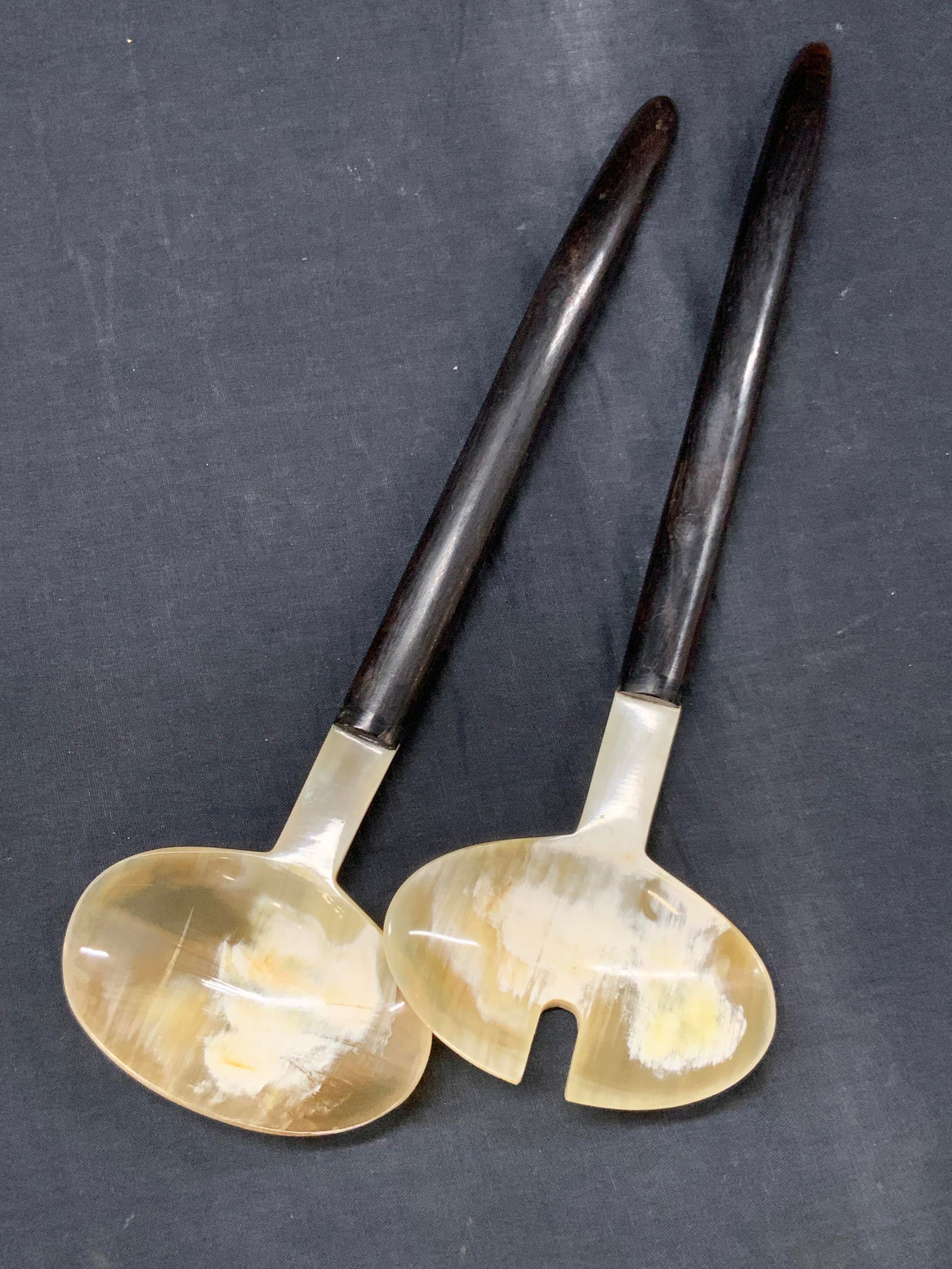 Pr Carved Horn Crafted Serving Utensils: Pair of polished horn crafted serving utensils with dark pieces as handles and lighter horn as cups, approx 12 inches long. Minor surface wearing to materials due to age and use. Horn utensils, horn d