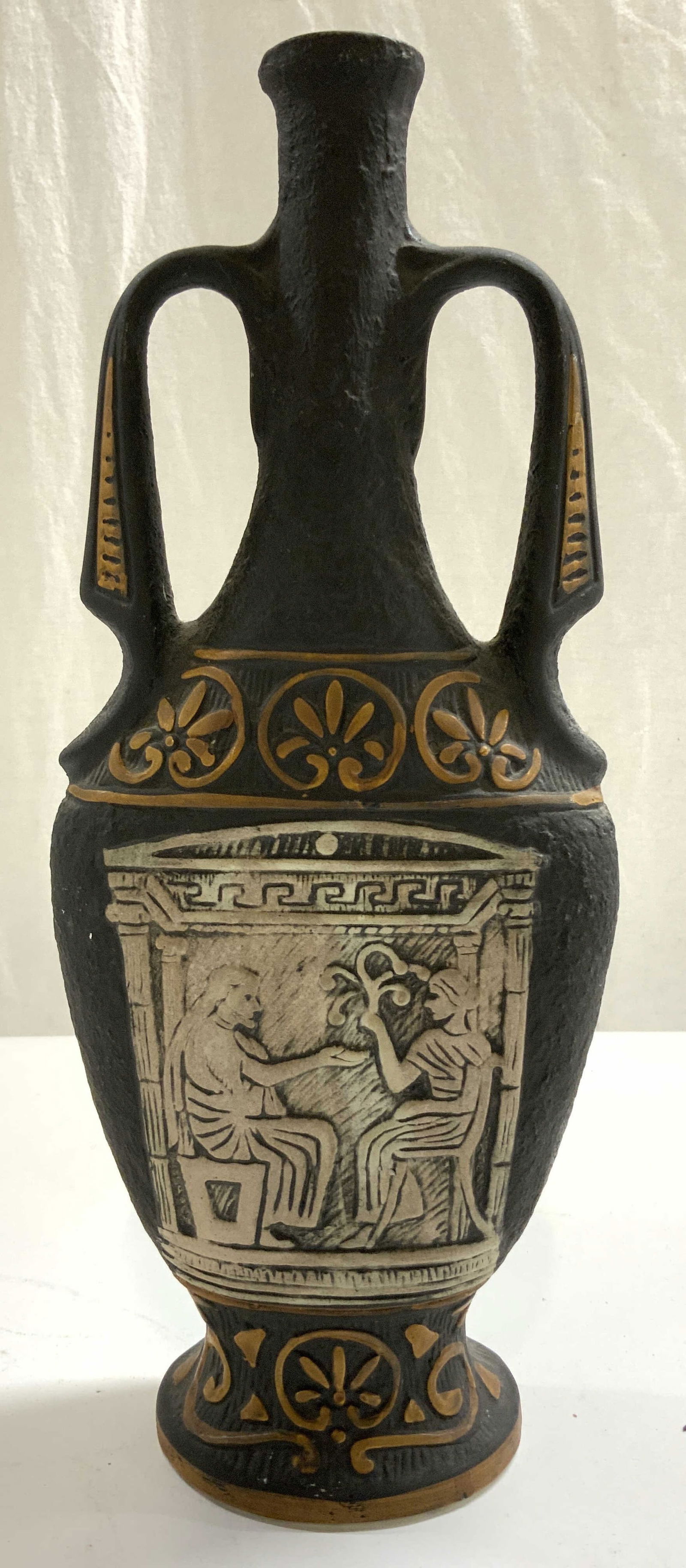 Greek Attic Limestone Terra Cotta Bottle Vessel: Bottle appears to be vintage. Piece is black with beveled slate toned detail of seated male and female figure. Piece also has light brown toned floral pattern and curl detail. Vessel has handles at ne